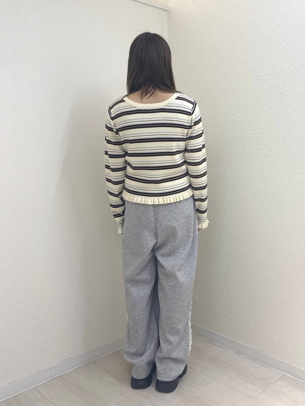 グレー系のスウェットパンツ、ブラウン系のローファー、ホワイト系のニット/セーターを着用したレディースの冬コーディネートの2枚目の写真