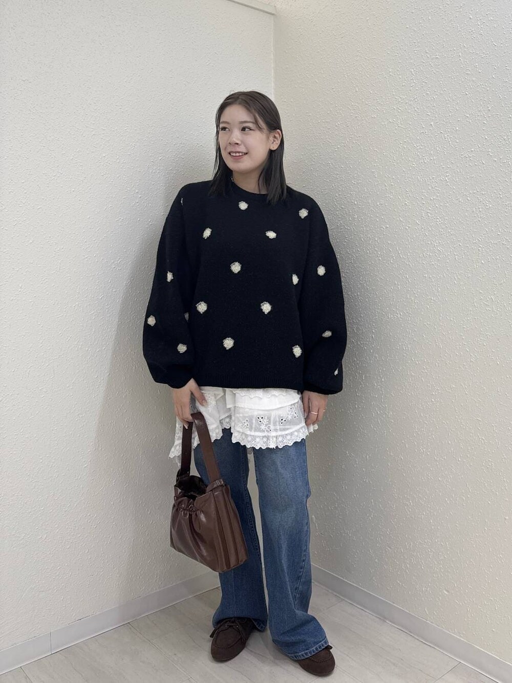 ブルー系のデニムパンツ、ホワイト系のスカート、ブラウン系のショルダーバッグを着用したレディースの冬コーディネートの2枚目の写真