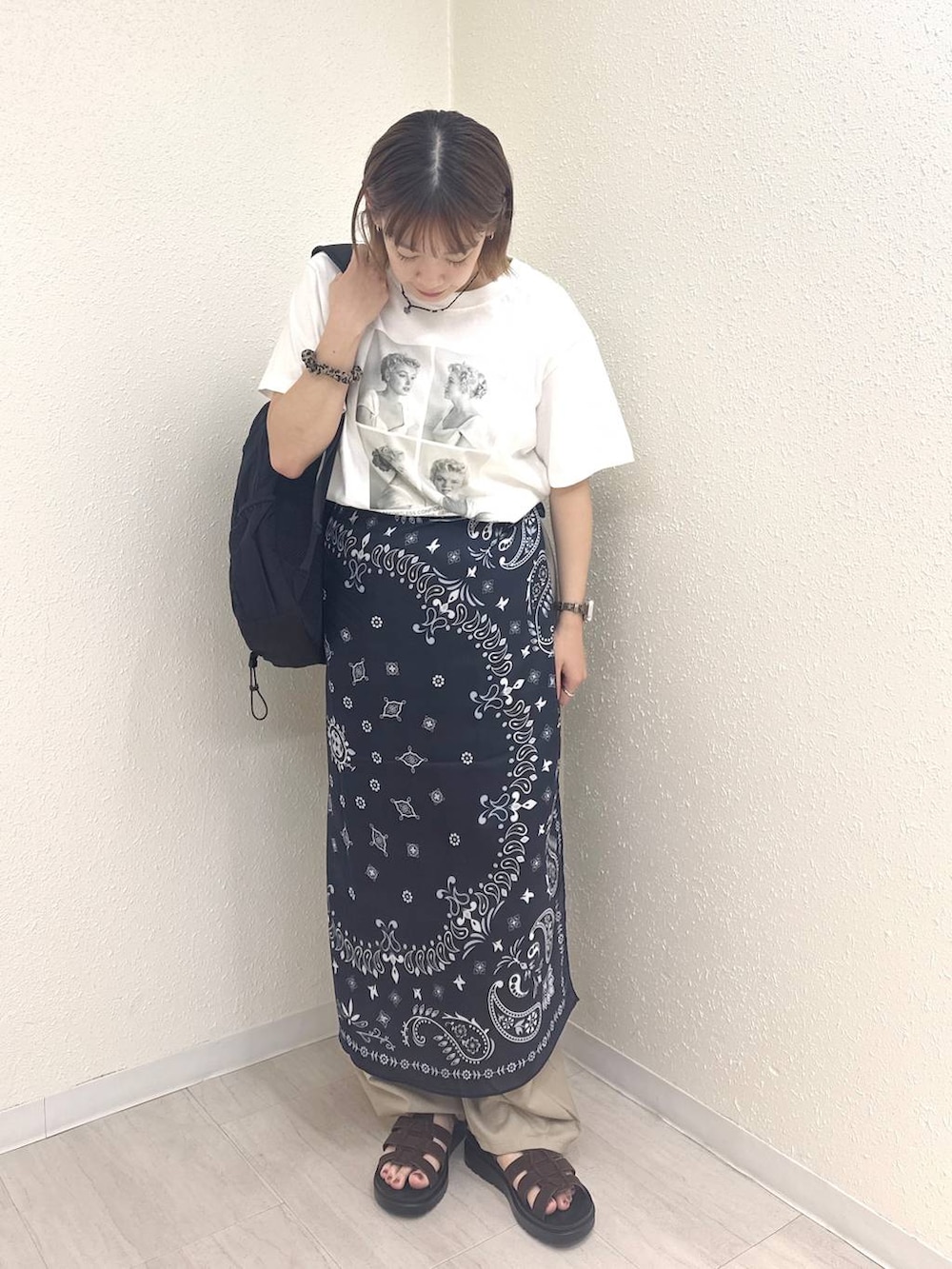 ベージュ系のその他パンツ、ブラウン系のサンダル、ホワイト系のTシャツ/カットソーを着用したレディースの夏コーディネートの2枚目の写真