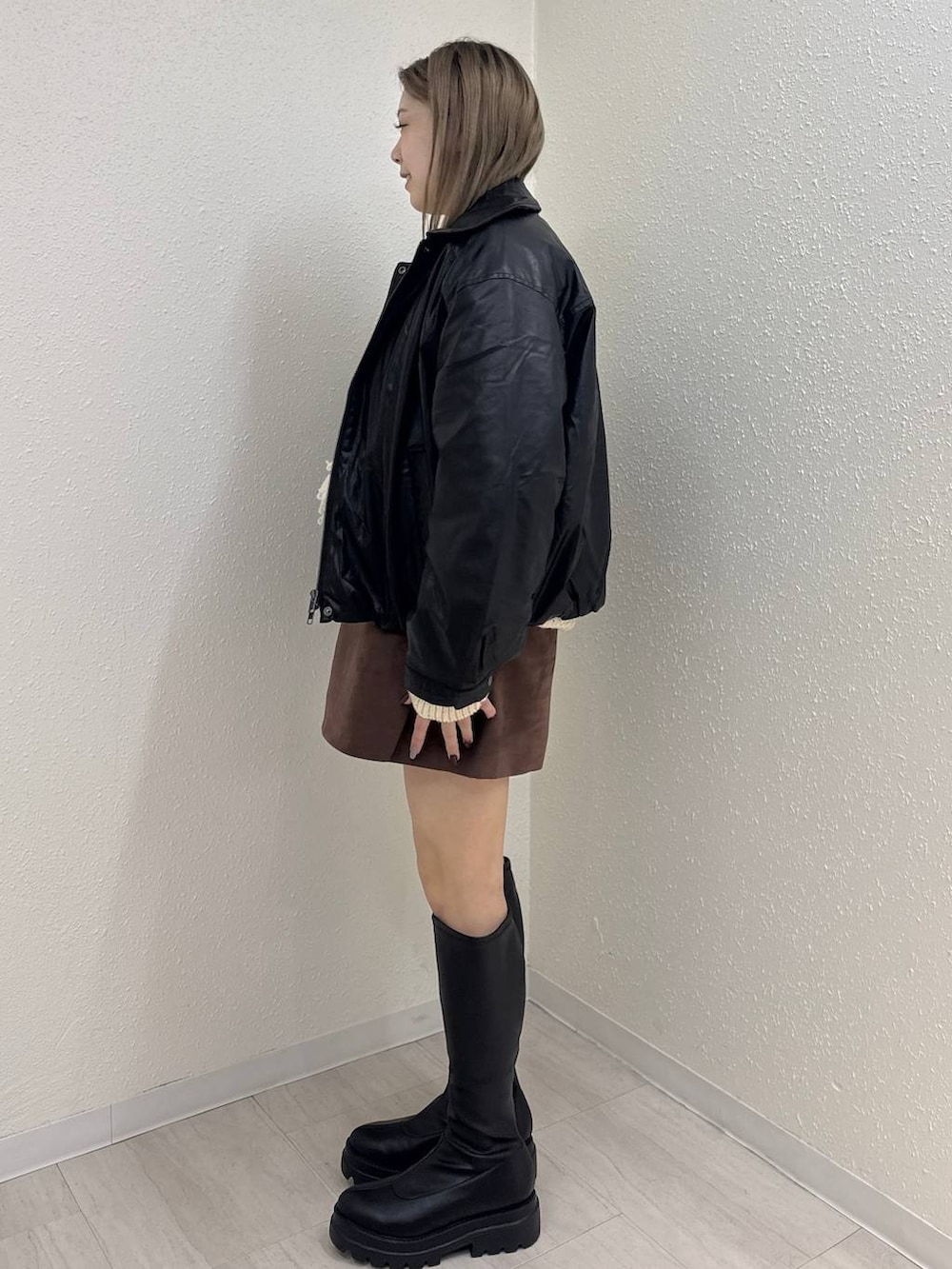 ブラック系のブルゾン、ブラウン系のスカート、ブラック系のブーツを着用したレディースの秋コーディネートの2枚目の写真