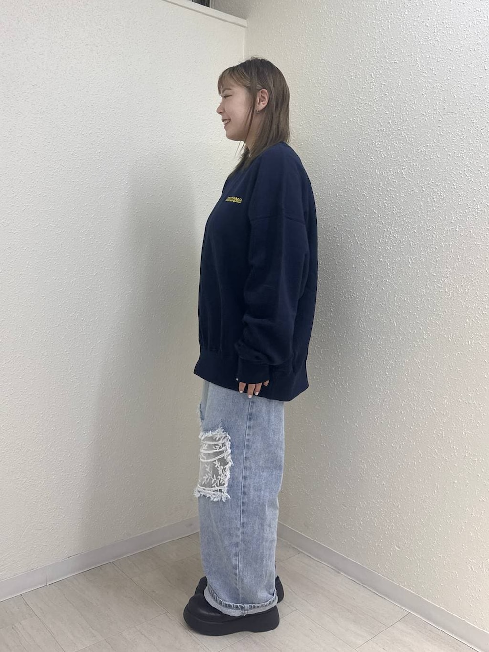 ブルー系のデニムパンツ、ブラック系のサンダル、ブルー系のスウェットを着用したレディースの冬コーディネートの3枚目の写真