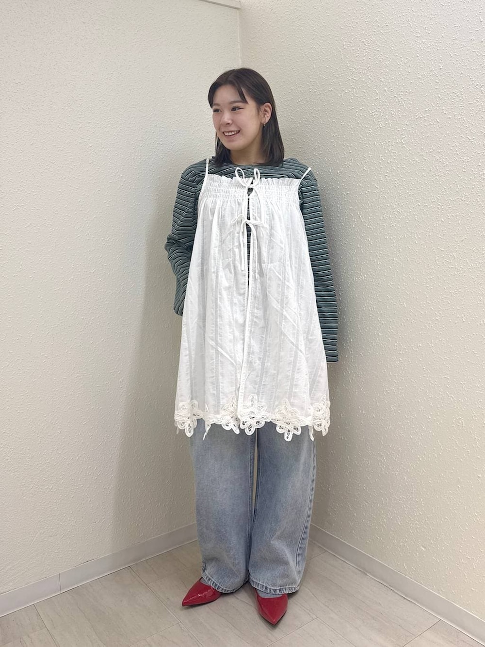 レッド系のパンプス、ブルー系のデニムパンツ、ホワイト系のワンピースを着用したレディースの春コーディネートの3枚目の写真