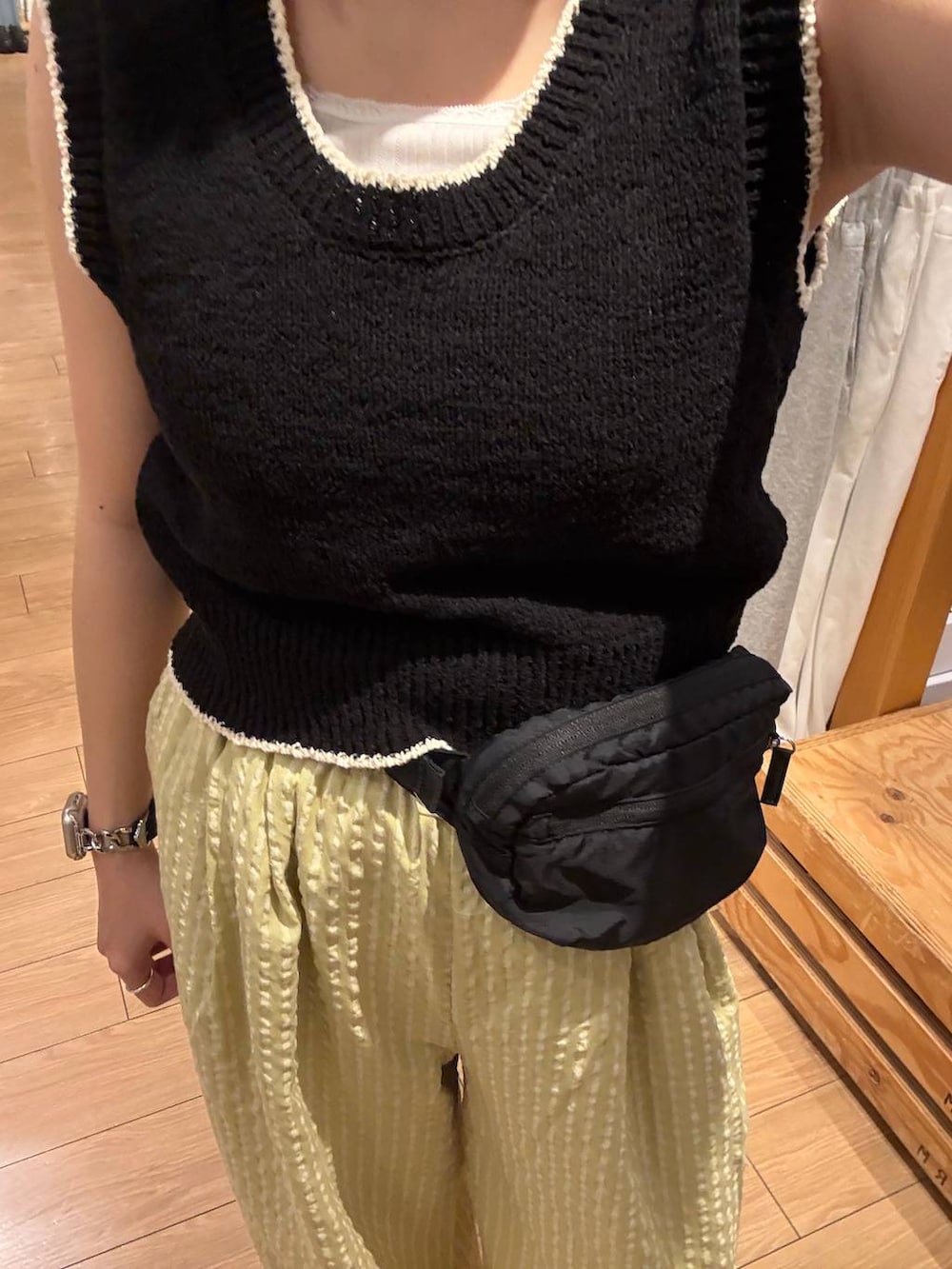 ブラック系のボディバッグ/ウエストポーチ、ホワイト系のサンダル、ブラック系のベストを着用したレディースの春コーディネートの3枚目の写真