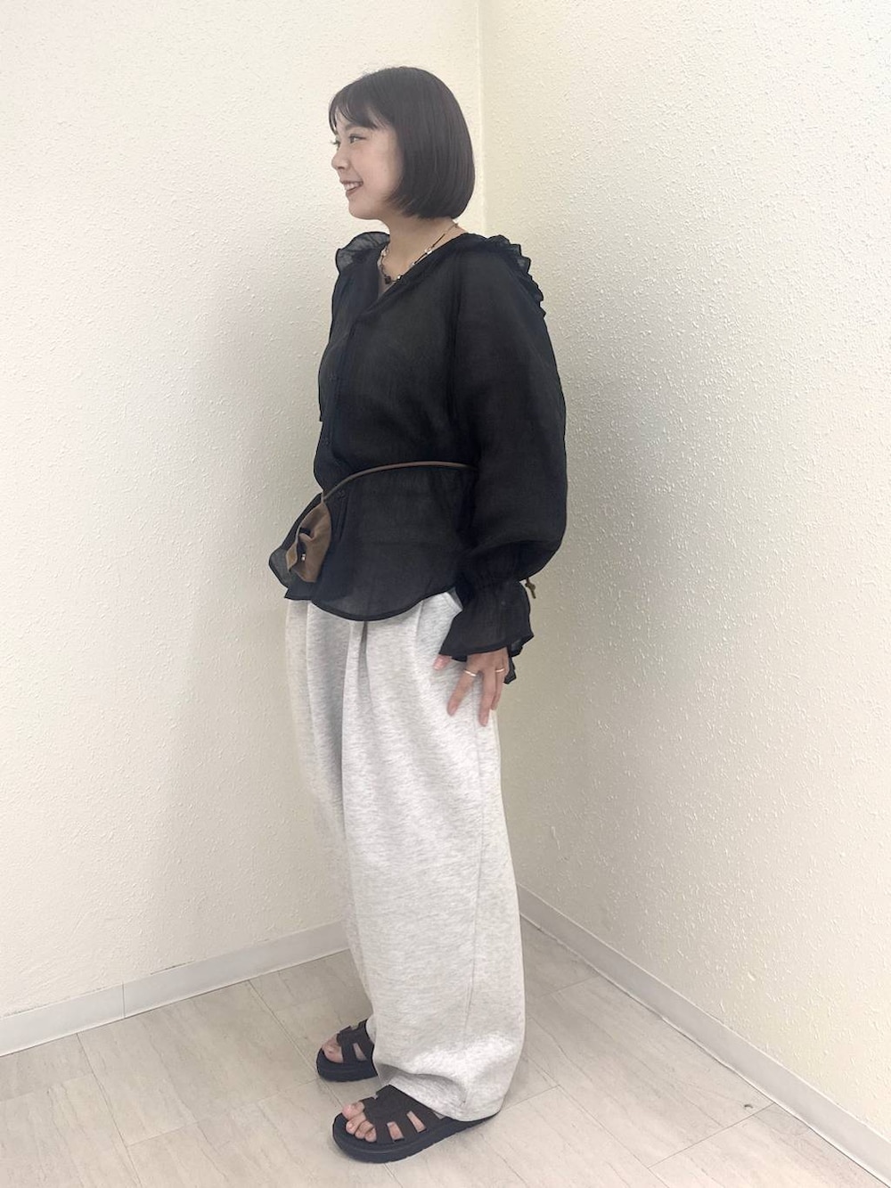 イエロー系のボディバッグ/ウエストポーチ、グレー系のスウェットパンツ、ブラック系のシャツ/ブラウスを着用したレディースの秋コーディネートの3枚目の写真