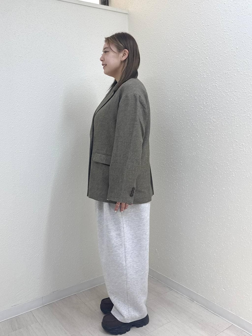 グレー系のスウェットパンツ、グレー系のテーラードジャケット、ブラウン系のローファーを着用したレディースの冬コーディネートの3枚目の写真