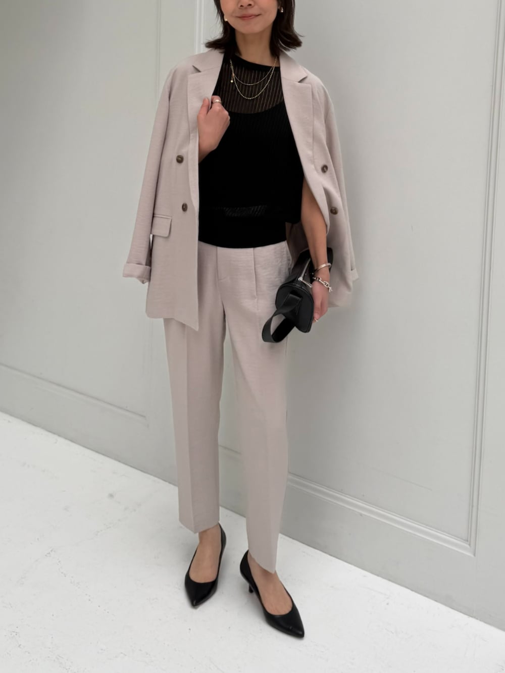 ベージュ系のスラックス、ベージュ系のテーラードジャケット、ブラック系のベストを着用したレディースの春コーディネートの2枚目の写真
