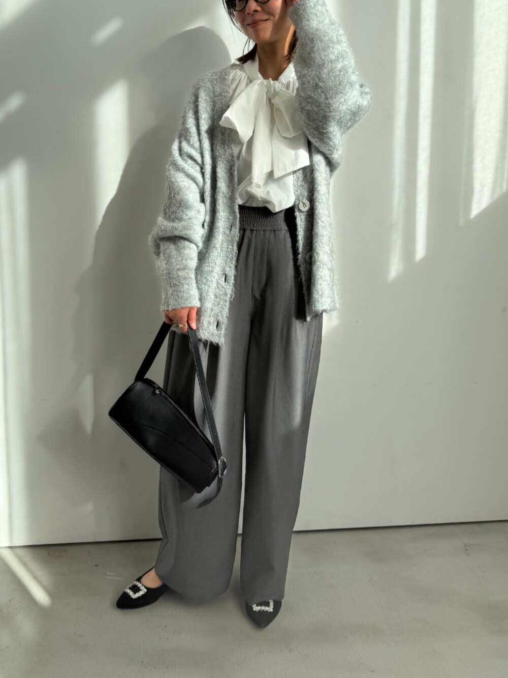 グレー系のスラックス、ホワイト系のシャツ/ブラウス、グレー系のカーディガン/ボレロを着用したレディースの冬コーディネートの2枚目の写真