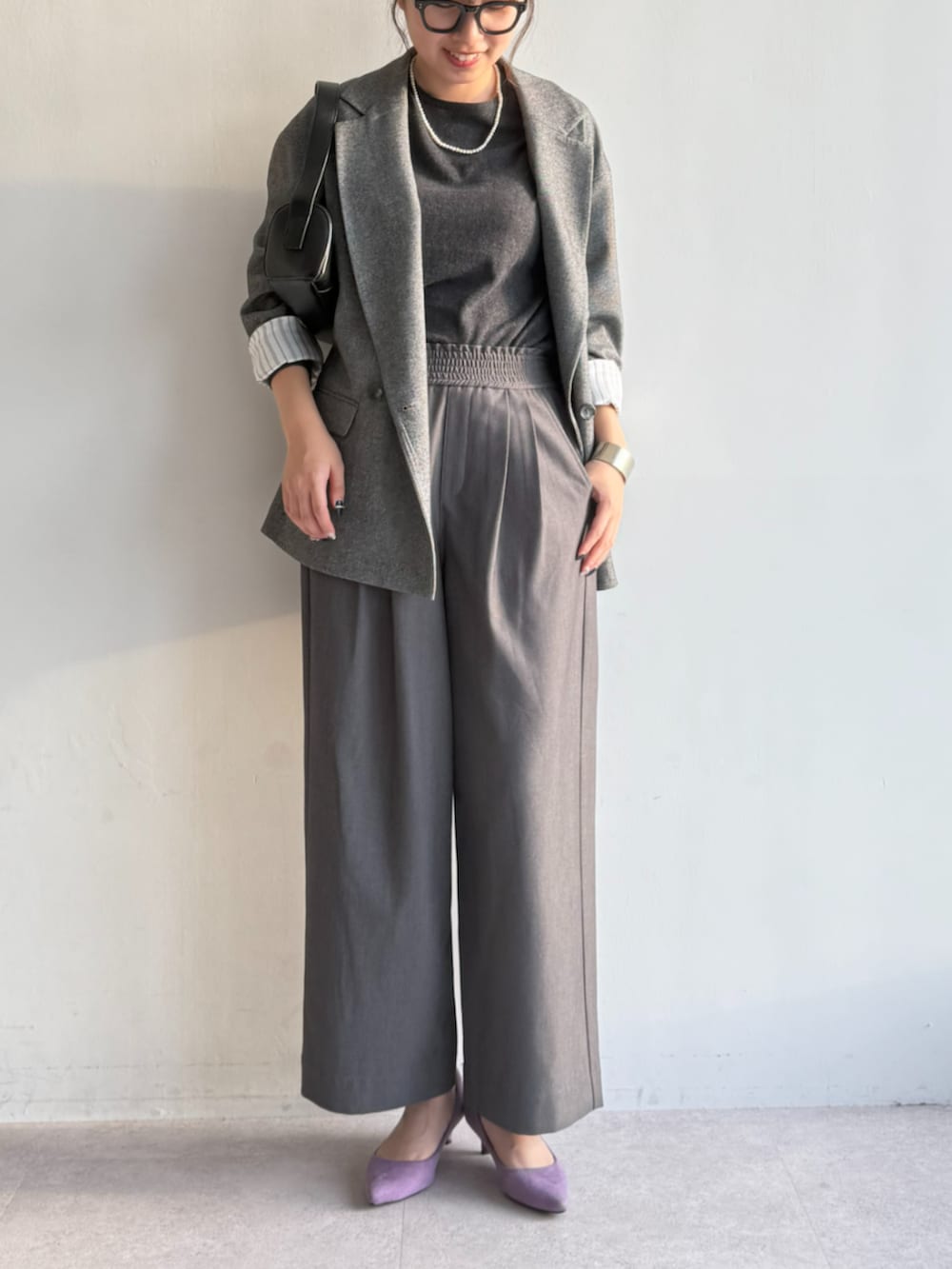 グレー系のスラックス、グレー系のニット/セーター、グレー系のテーラードジャケットを着用したレディースの秋コーディネートの2枚目の写真