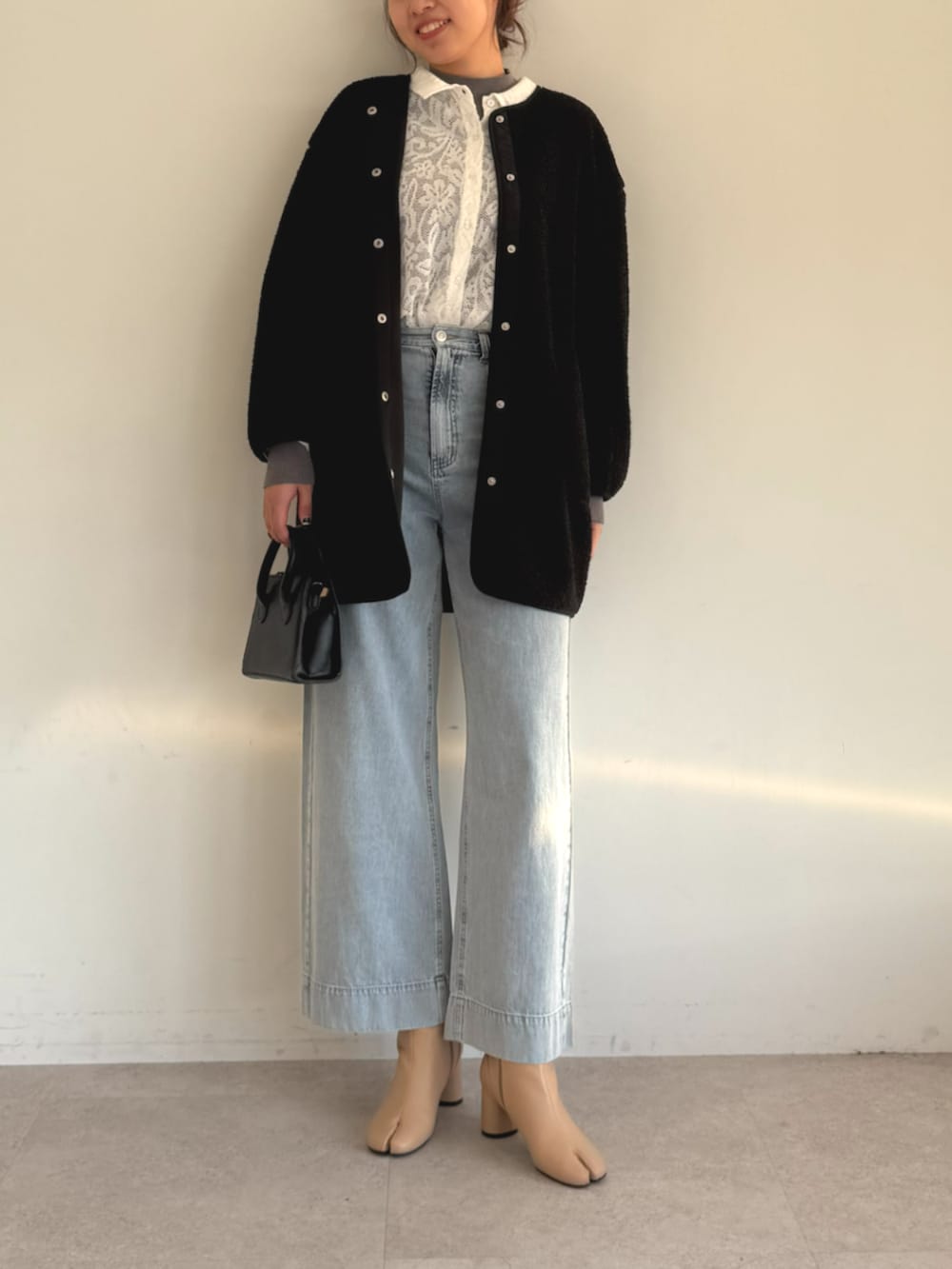 ホワイト系のカーディガン/ボレロ、ブルー系のデニムパンツ、グレー系のノーカラーコートを着用したレディースの秋コーディネートの2枚目の写真