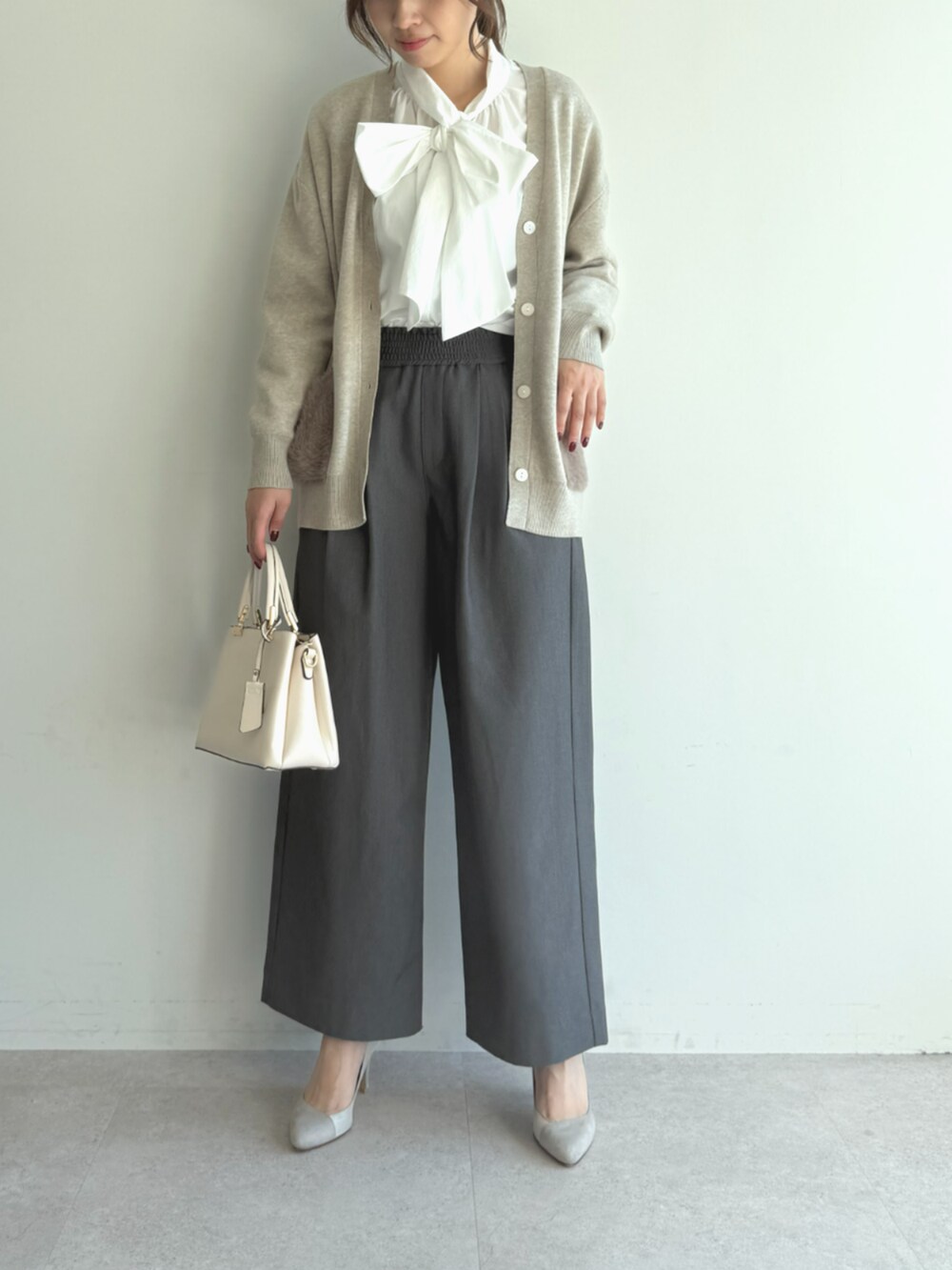 グレー系のスラックス、ホワイト系のシャツ/ブラウス、ベージュ系のカーディガン/ボレロを着用したレディースの秋コーディネートの2枚目の写真
