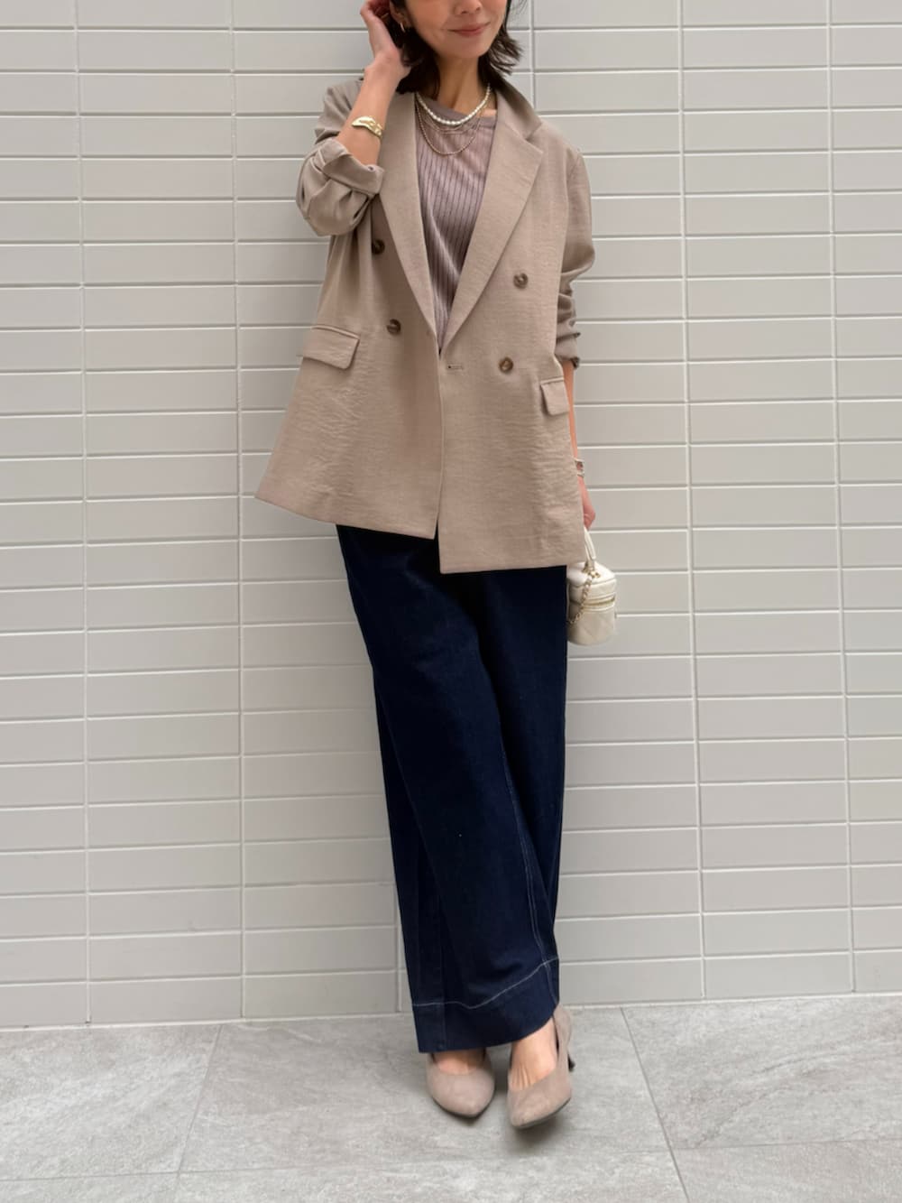 ブルー系のデニムパンツ、ブラウン系のベスト、ブラウン系のテーラードジャケットを着用したレディースの春コーディネートの2枚目の写真