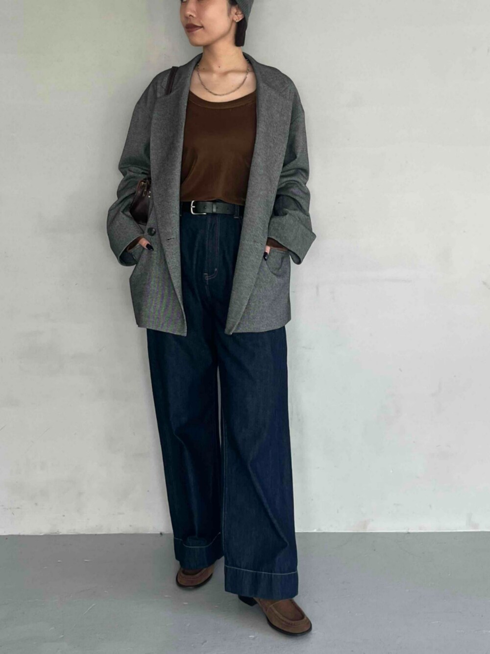 グレー系のテーラードジャケット、ブラウン系のTシャツ/カットソー、ブルー系のデニムパンツを着用したレディースの秋コーディネートの2枚目の写真