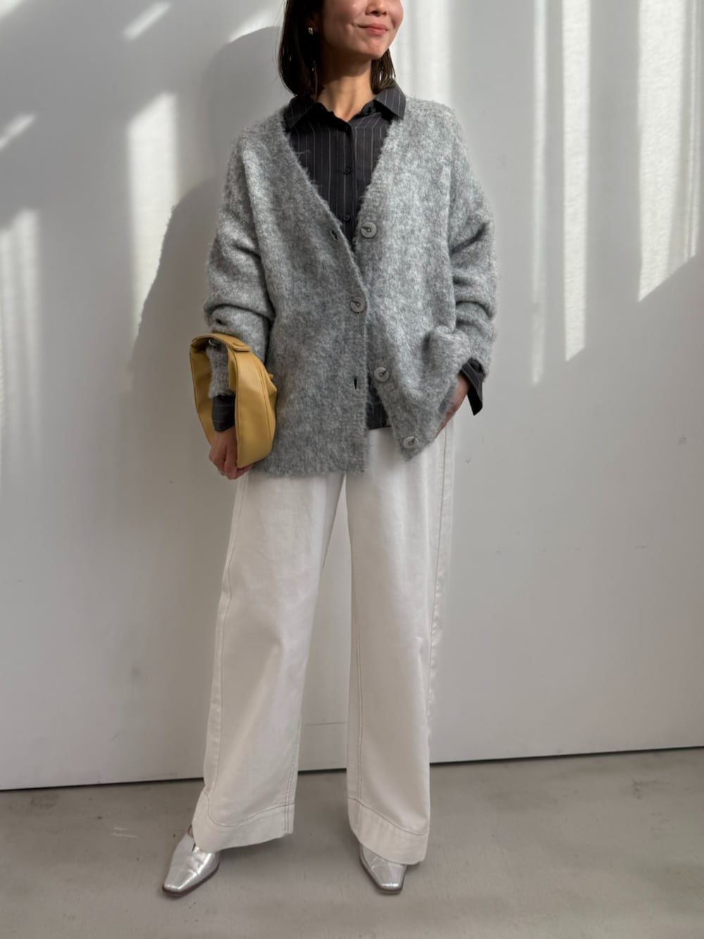 グレー系のシャツ/ブラウス、ホワイト系のデニムパンツ、グレー系のカーディガン/ボレロを着用したレディースの冬コーディネートの2枚目の写真