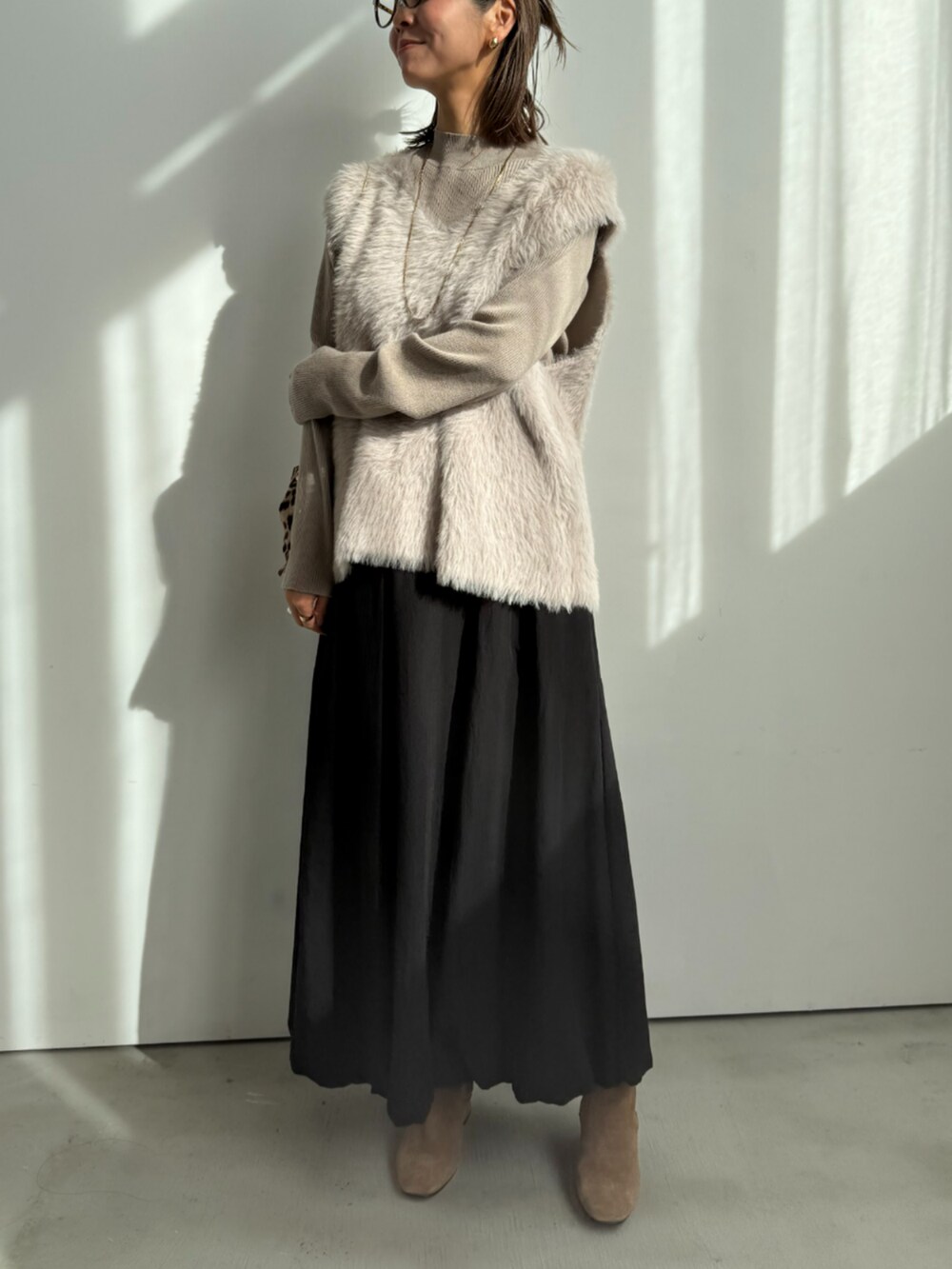 ベージュ系のニット/セーター、ブラック系のスカートを着用したレディースの冬コーディネートの2枚目の写真