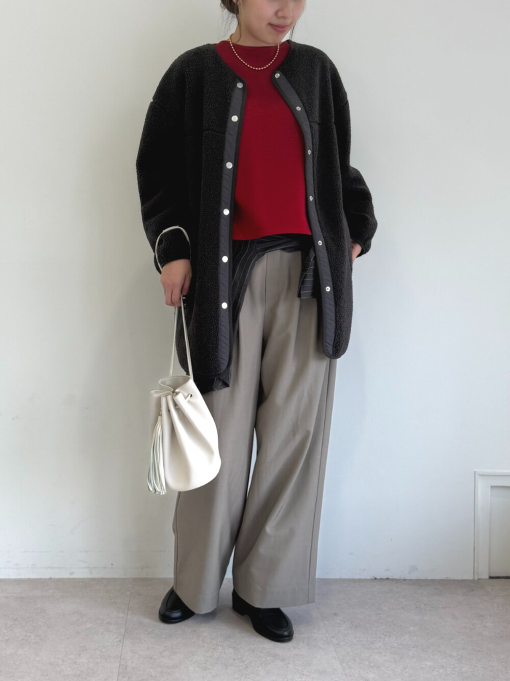 ベージュ系のスラックス、レッド系のニット/セーター、ブラック系のノーカラーコートを着用したレディースの秋コーディネートの2枚目の写真