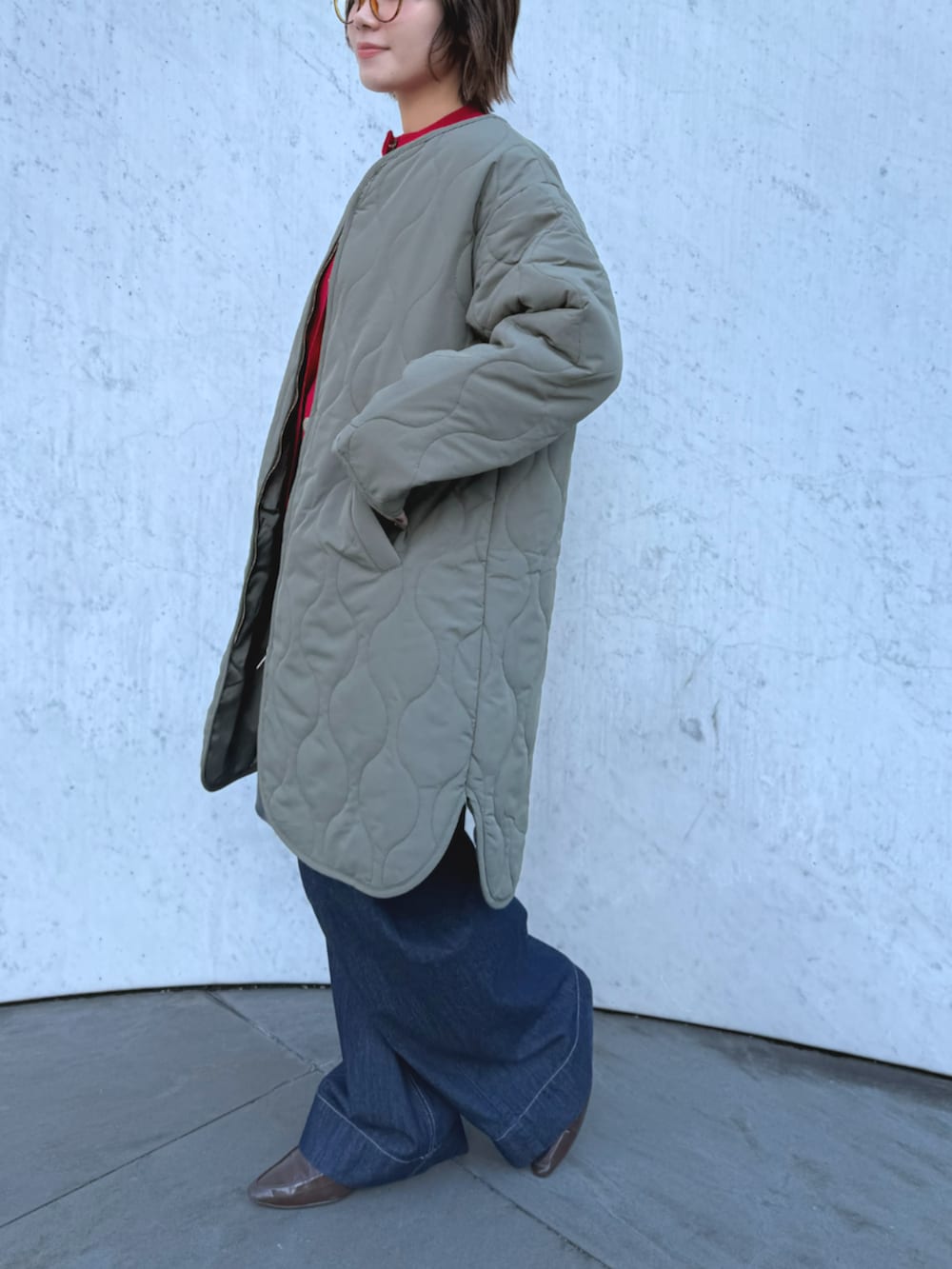 ブルー系のデニムパンツ、グリーン系のその他アウター、レッド系のニット/セーターを着用したレディースの秋コーディネートの2枚目の写真