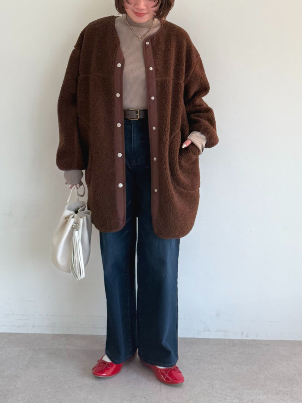 ベージュ系のニット/セーター、ブラウン系のノーカラーコート、ブルー系のその他パンツを着用したレディースの秋コーディネートの2枚目の写真