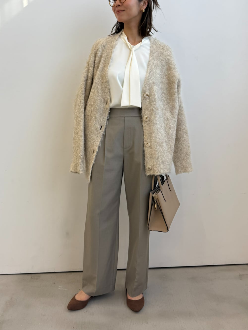 ベージュ系のカーディガン/ボレロ、ホワイト系のシャツ/ブラウス、ベージュ系のスラックスを着用したレディースの冬コーディネートの2枚目の写真