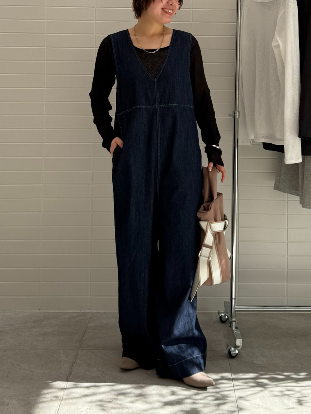 ブルー系のつなぎ/オールインワン、ブラウン系のトートバッグ、ブラック系のTシャツ/カットソーを着用したレディースの春コーディネートの2枚目の写真