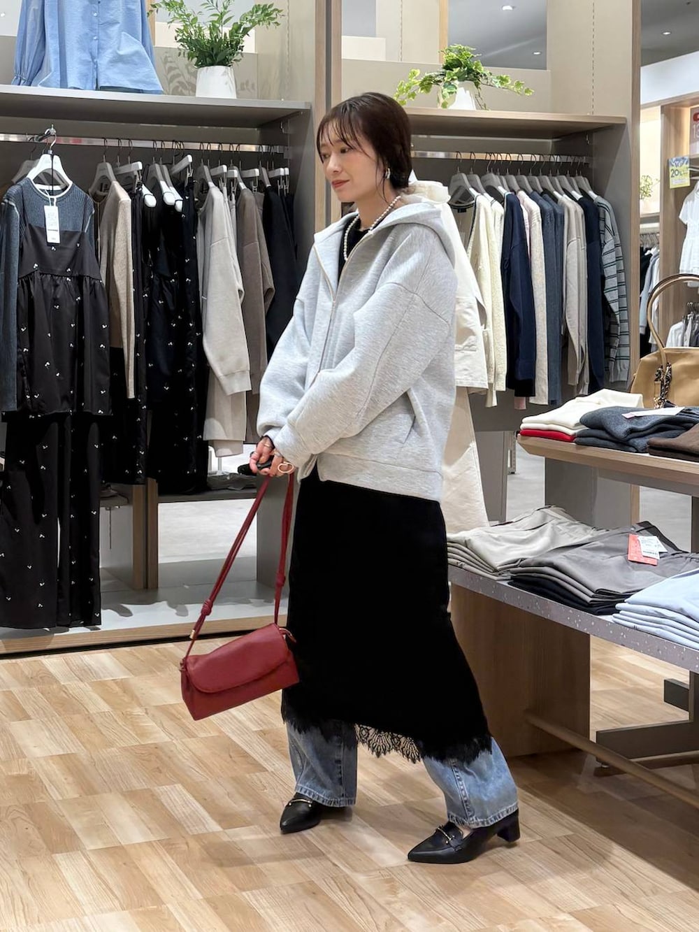 レッド系のショルダーバッグ、ブラック系のTシャツ/カットソー、ブルー系のデニムパンツを着用したレディースの春コーディネートの2枚目の写真