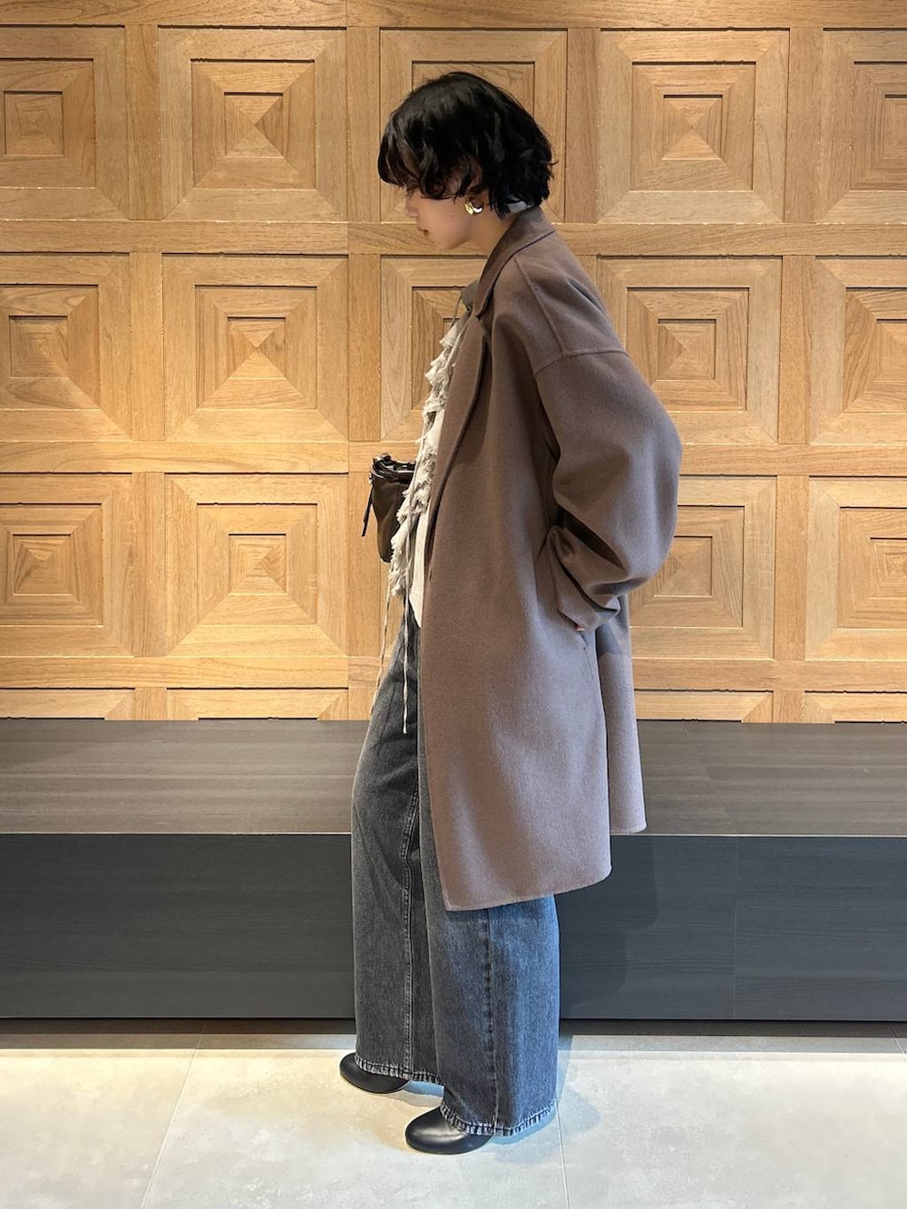 ブラック系のデニムパンツ、ブラウン系のチェスターコート、ベージュ系のシャツ/ブラウスを着用したレディースの秋コーディネートの4枚目の写真