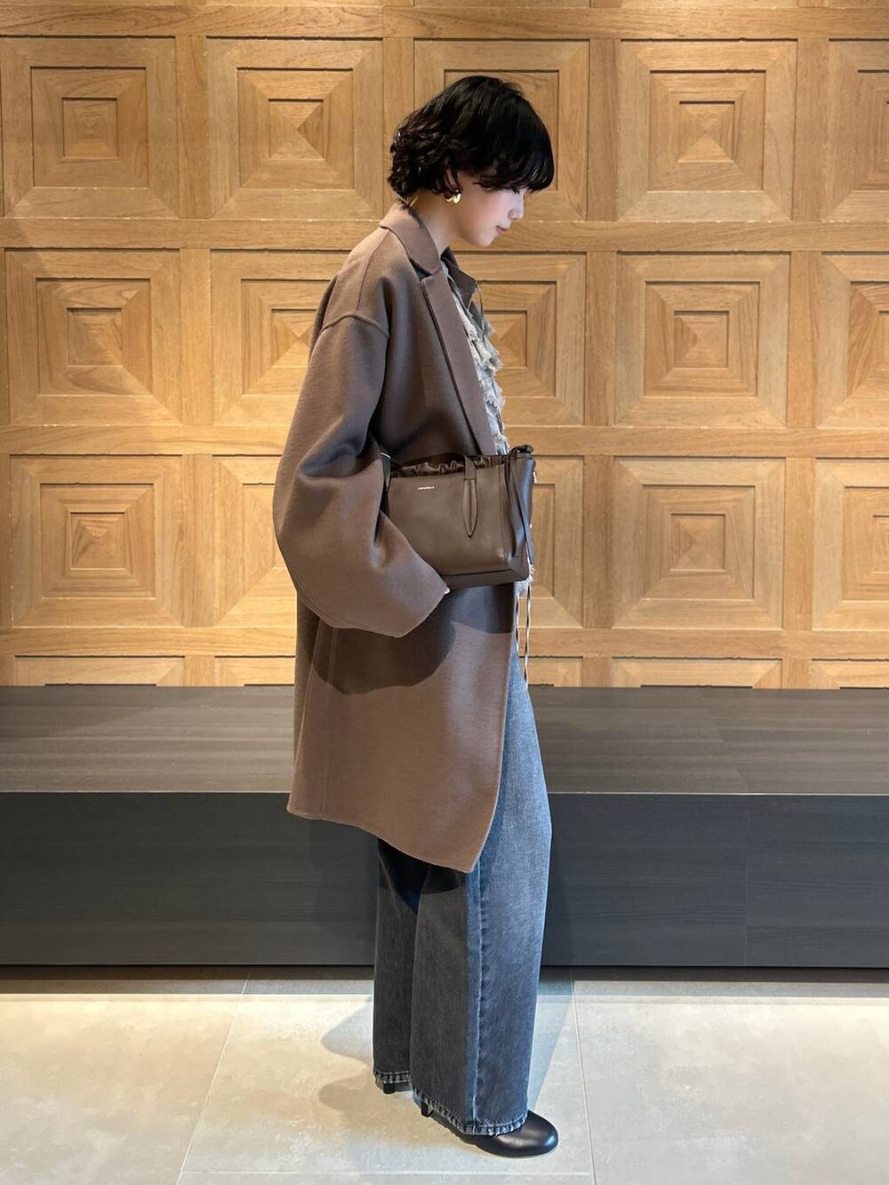 ブラック系のデニムパンツ、ブラウン系のチェスターコート、ベージュ系のシャツ/ブラウスを着用したレディースの秋コーディネートの2枚目の写真