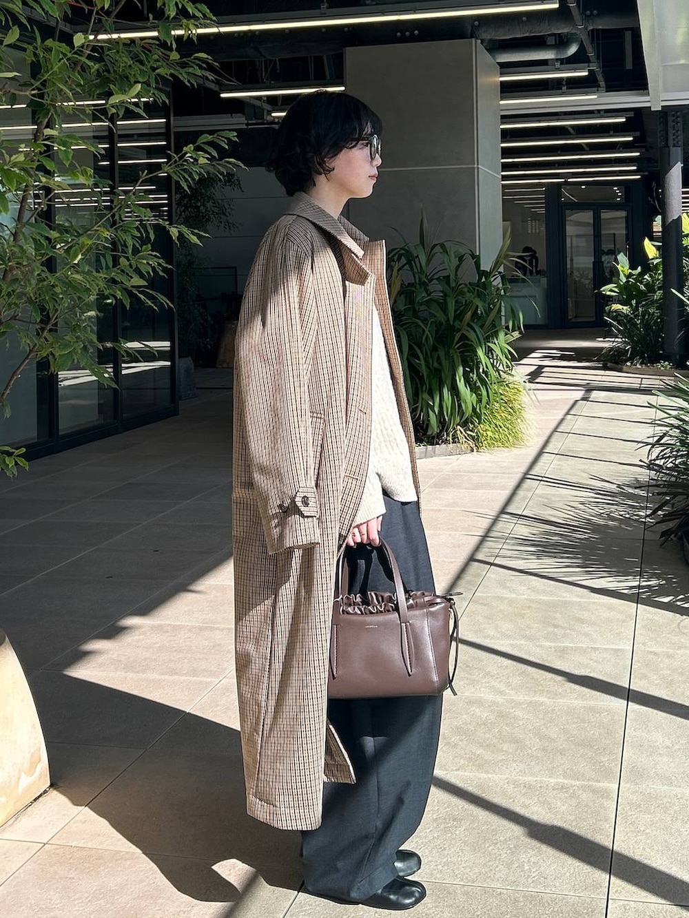 ベージュ系のチェスターコート、ホワイト系のニット/セーター、グレー系のその他パンツを着用したレディースの秋コーディネートの2枚目の写真