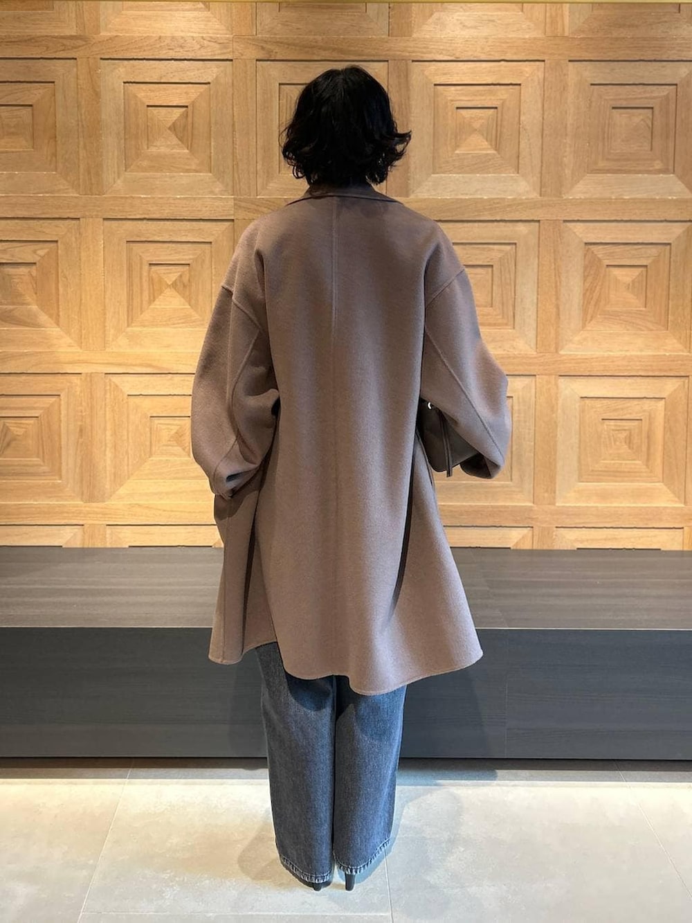 ブラック系のデニムパンツ、ブラウン系のチェスターコート、ベージュ系のシャツ/ブラウスを着用したレディースの秋コーディネートの3枚目の写真