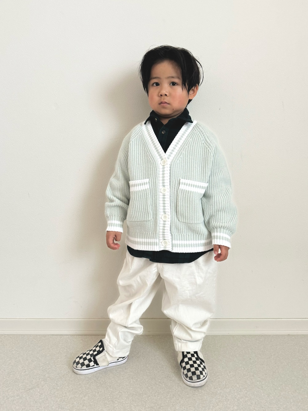 ブラック系のスニーカー、ホワイト系のチノパンツ、グリーン系のカーディガン/ボレロを着用したキッズの春コーディネートの2枚目の写真