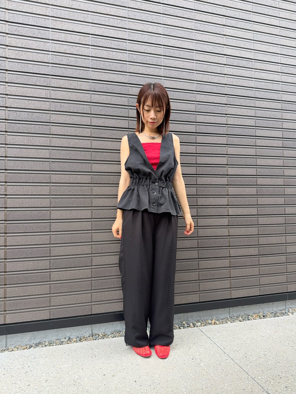 レッド系のキャミソール、ブラック系のチノパンツ、レッド系のパンプスを着用したレディースの夏コーディネートの2枚目の写真