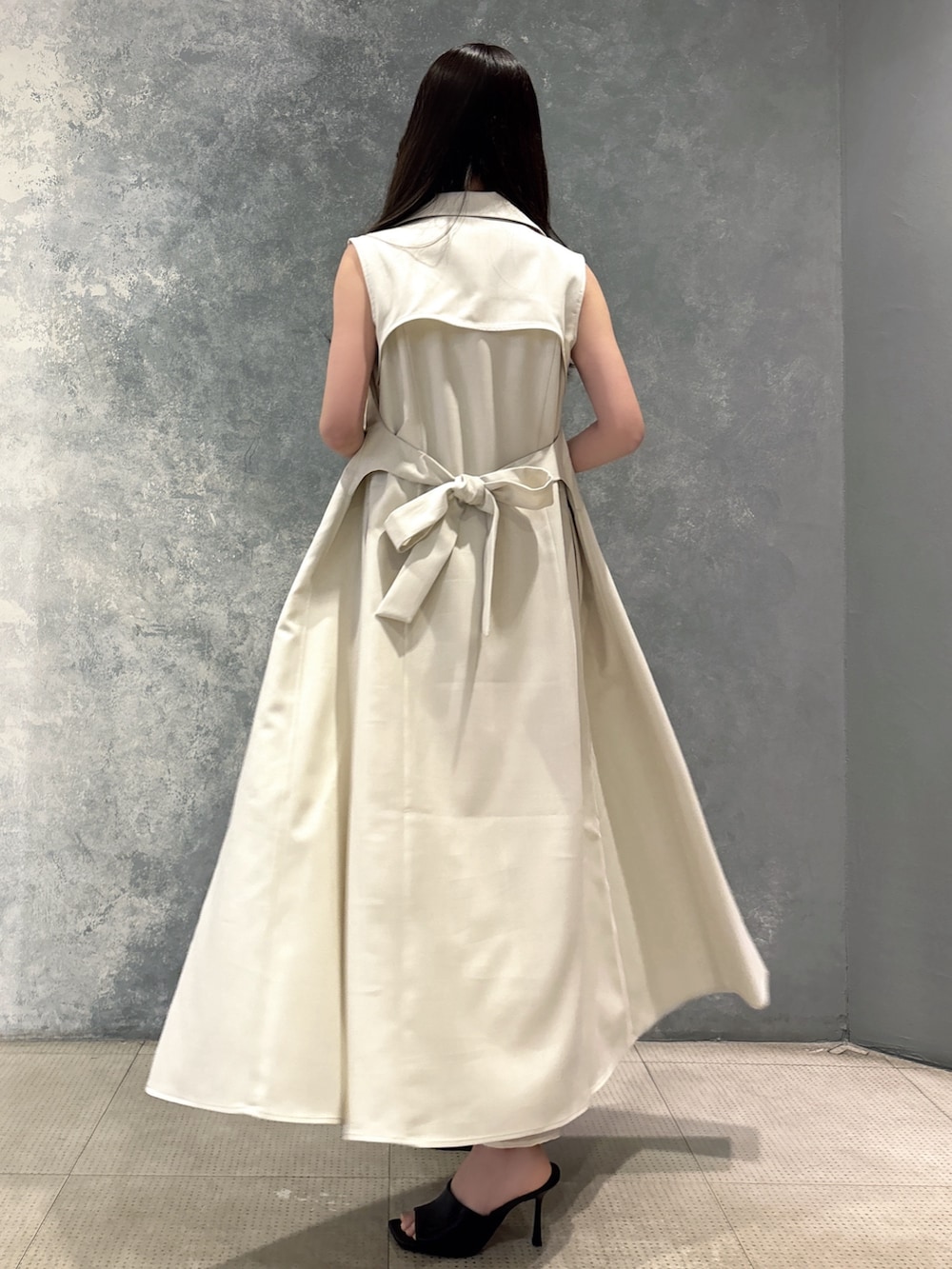 ブラック系のサンダル、ホワイト系のベスト、ホワイト系のワンピースを着用したレディースの夏コーディネートの2枚目の写真