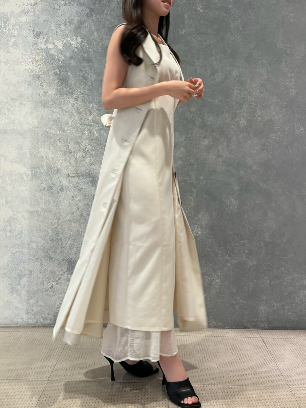 ブラック系のサンダル、ホワイト系のベスト、ホワイト系のワンピースを着用したレディースの夏コーディネートの3枚目の写真