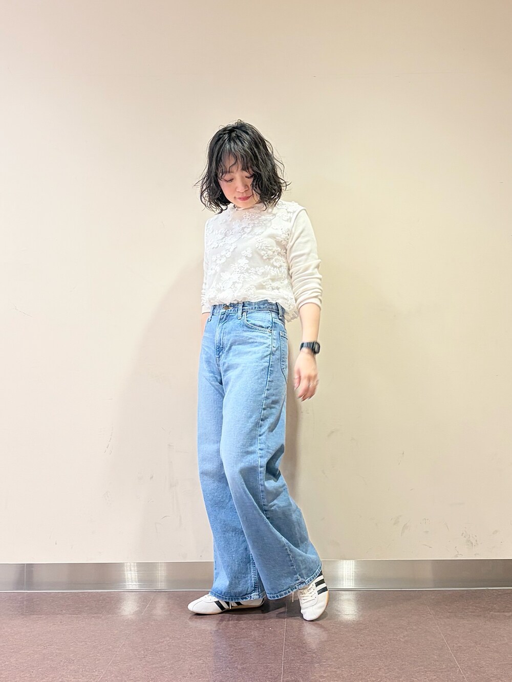 ホワイト系のスニーカー、ブルー系のデニムパンツ、ホワイト系のタンクトップを着用したレディースの春コーディネートの4枚目の写真