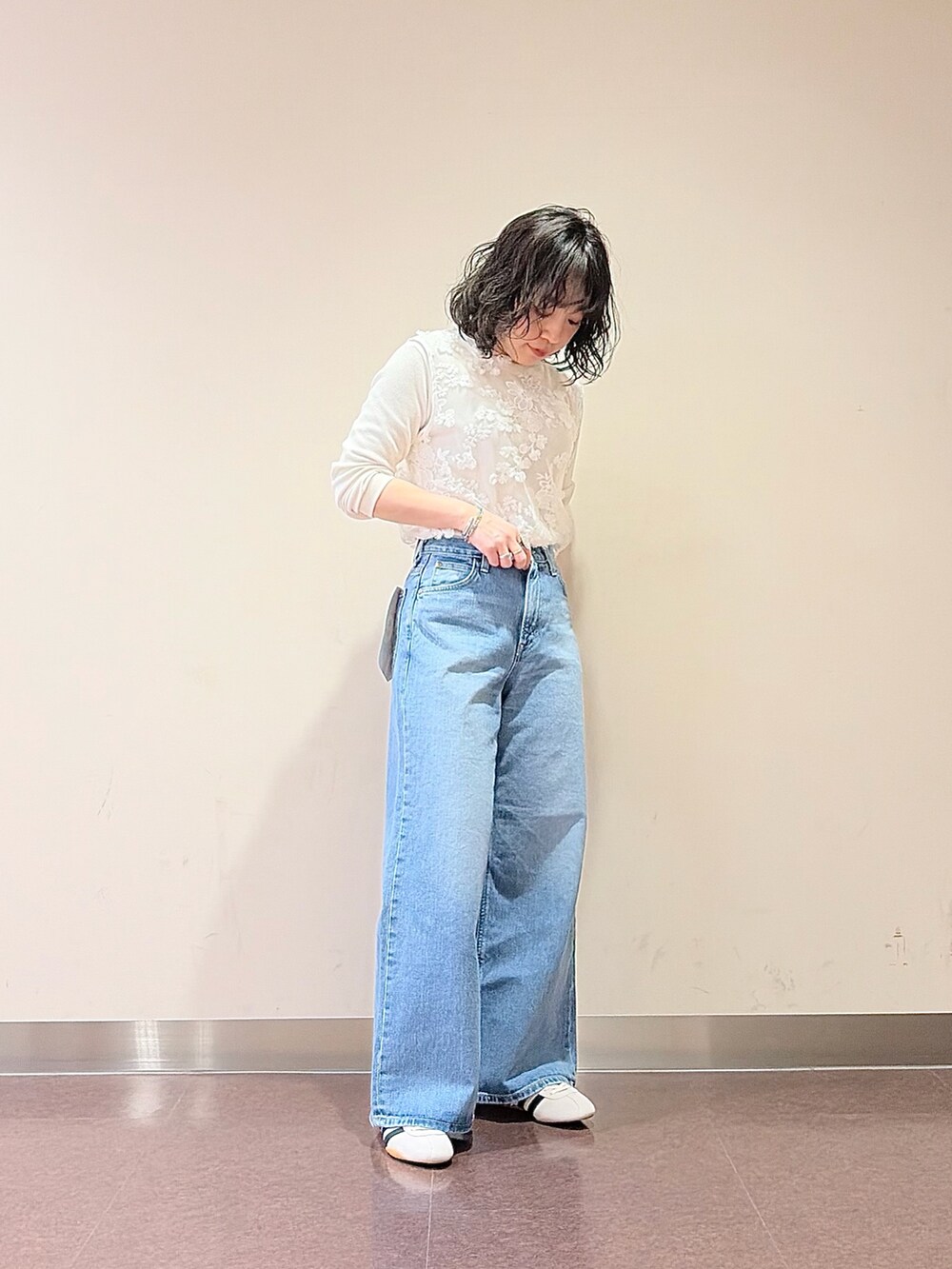 ホワイト系のスニーカー、ブルー系のデニムパンツ、ホワイト系のタンクトップを着用したレディースの春コーディネートの2枚目の写真