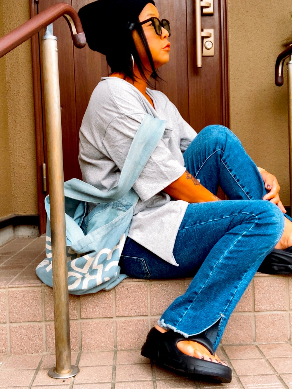 グレー系のTシャツ/カットソー、ブルー系のデニムパンツ、ブルー系のショルダーバッグを着用したレディースの夏コーディネートの3枚目の写真