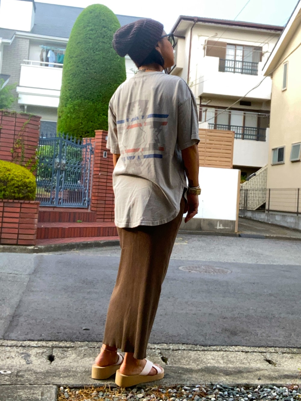 ブラウン系のスカート、ホワイト系のサンダル、ベージュ系のTシャツ/カットソーを着用したレディースの夏コーディネートの2枚目の写真