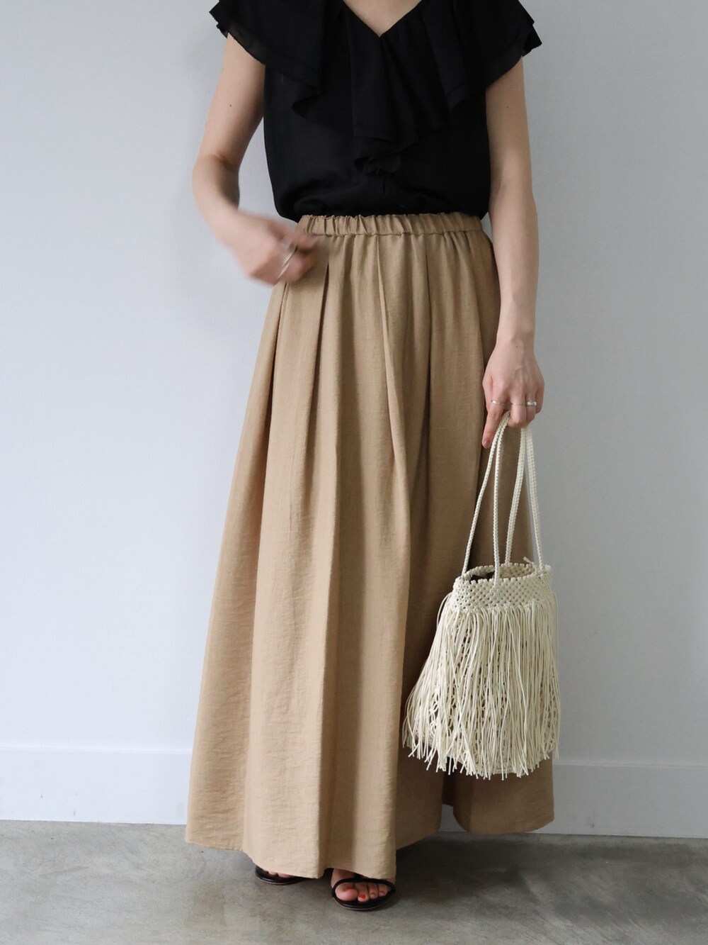 ブラック系のシャツ/ブラウス、ベージュ系のスカート、ブラック系のサンダルを着用したレディースの夏コーディネートの5枚目の写真