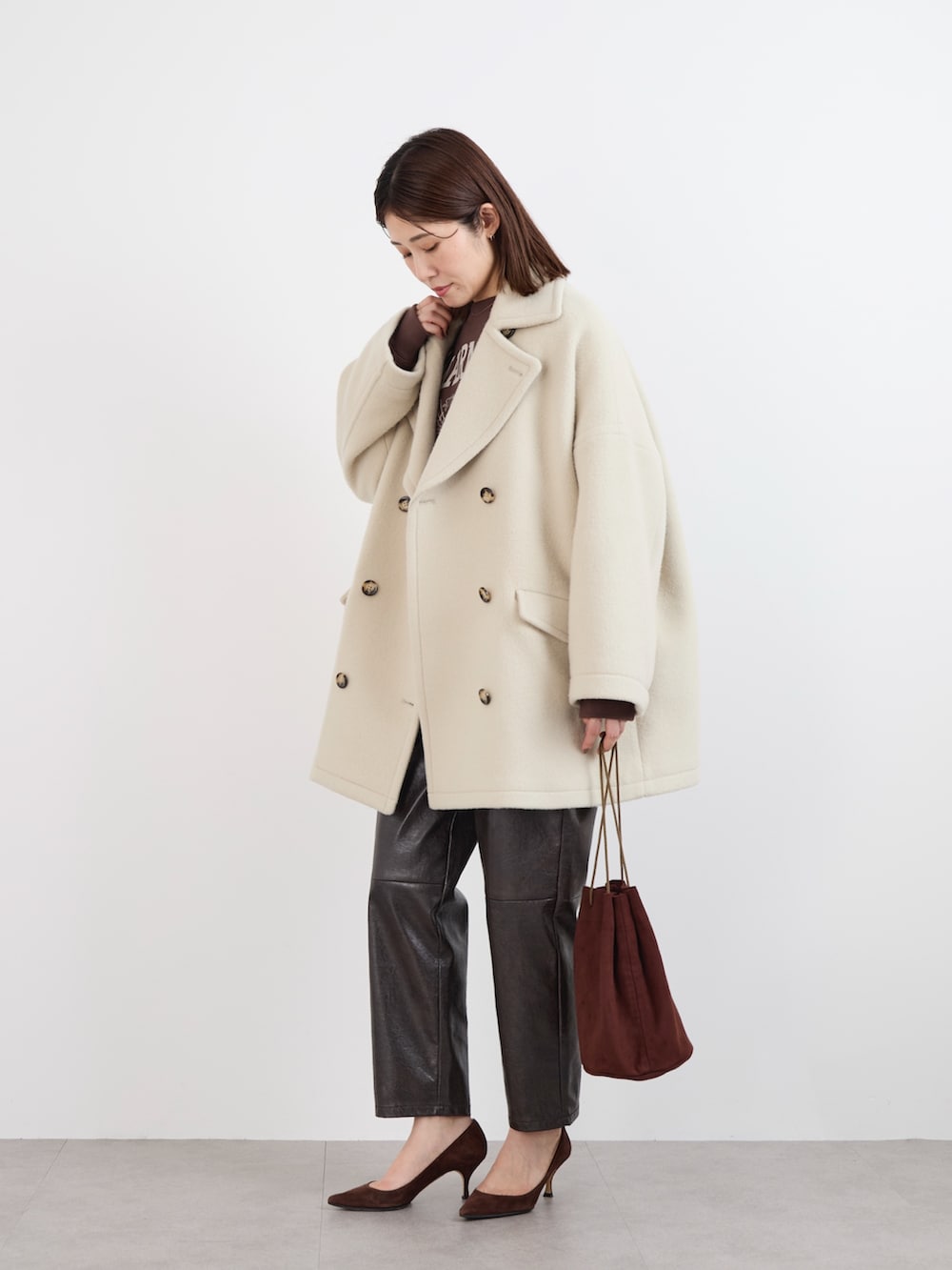 ブラウン系のスウェット、ホワイト系のTシャツ/カットソー、ベージュ系のピーコートを着用したレディースの冬コーディネートの3枚目の写真
