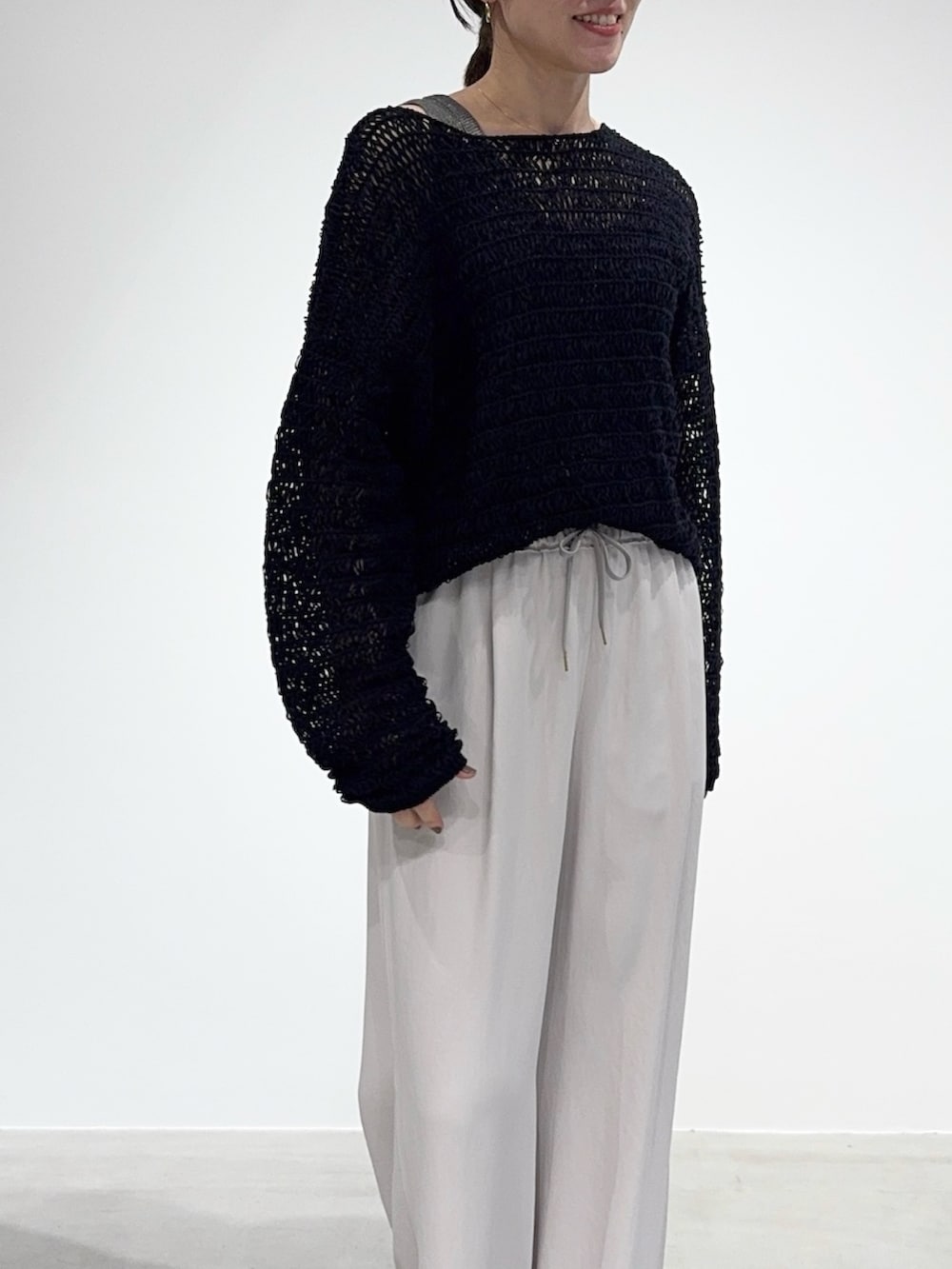 ホワイト系のその他パンツ、ブラック系のニット/セーター、グレー系のタンクトップを着用したレディースの春コーディネートの2枚目の写真