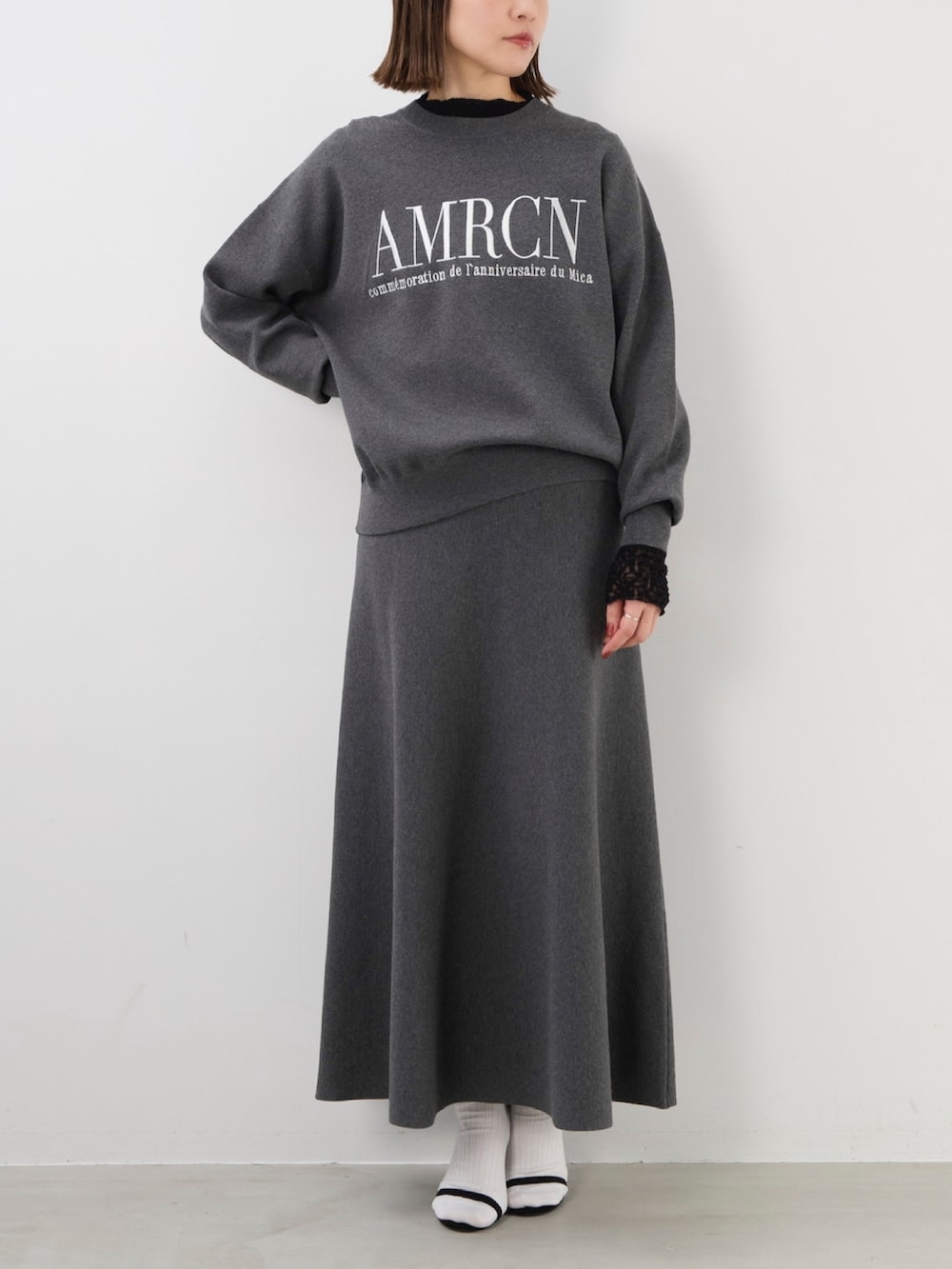 グレー系のニット/セーター、グレー系のスカート、ブラック系のTシャツ/カットソーを着用したレディースの秋コーディネートの2枚目の写真