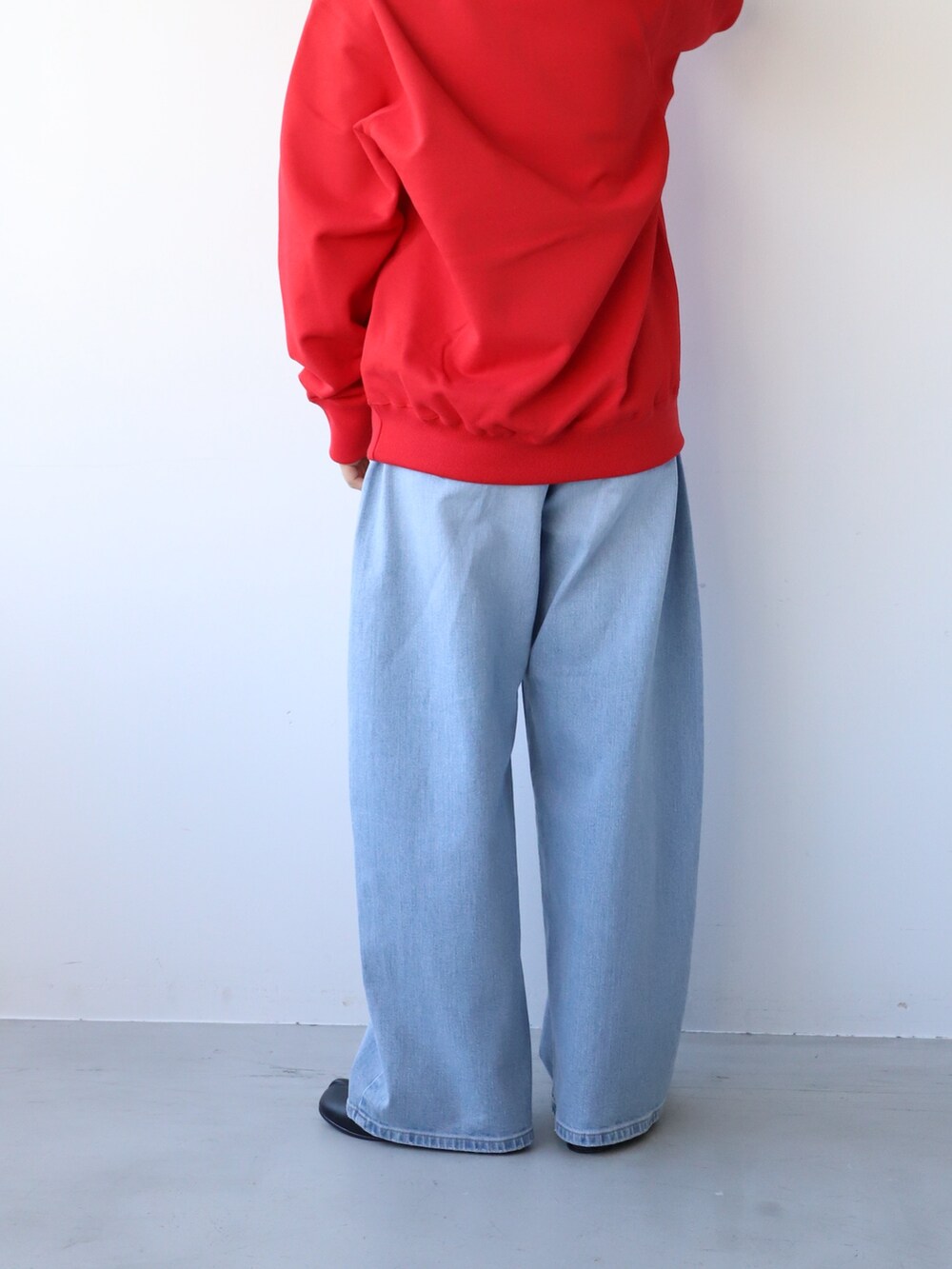 ブルー系のデニムパンツ、ブラック系のバレエシューズ、レッド系のパーカーを着用したレディースの秋コーディネートの5枚目の写真