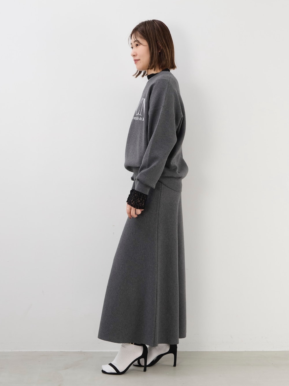 グレー系のニット/セーター、グレー系のスカート、ブラック系のTシャツ/カットソーを着用したレディースの秋コーディネートの4枚目の写真