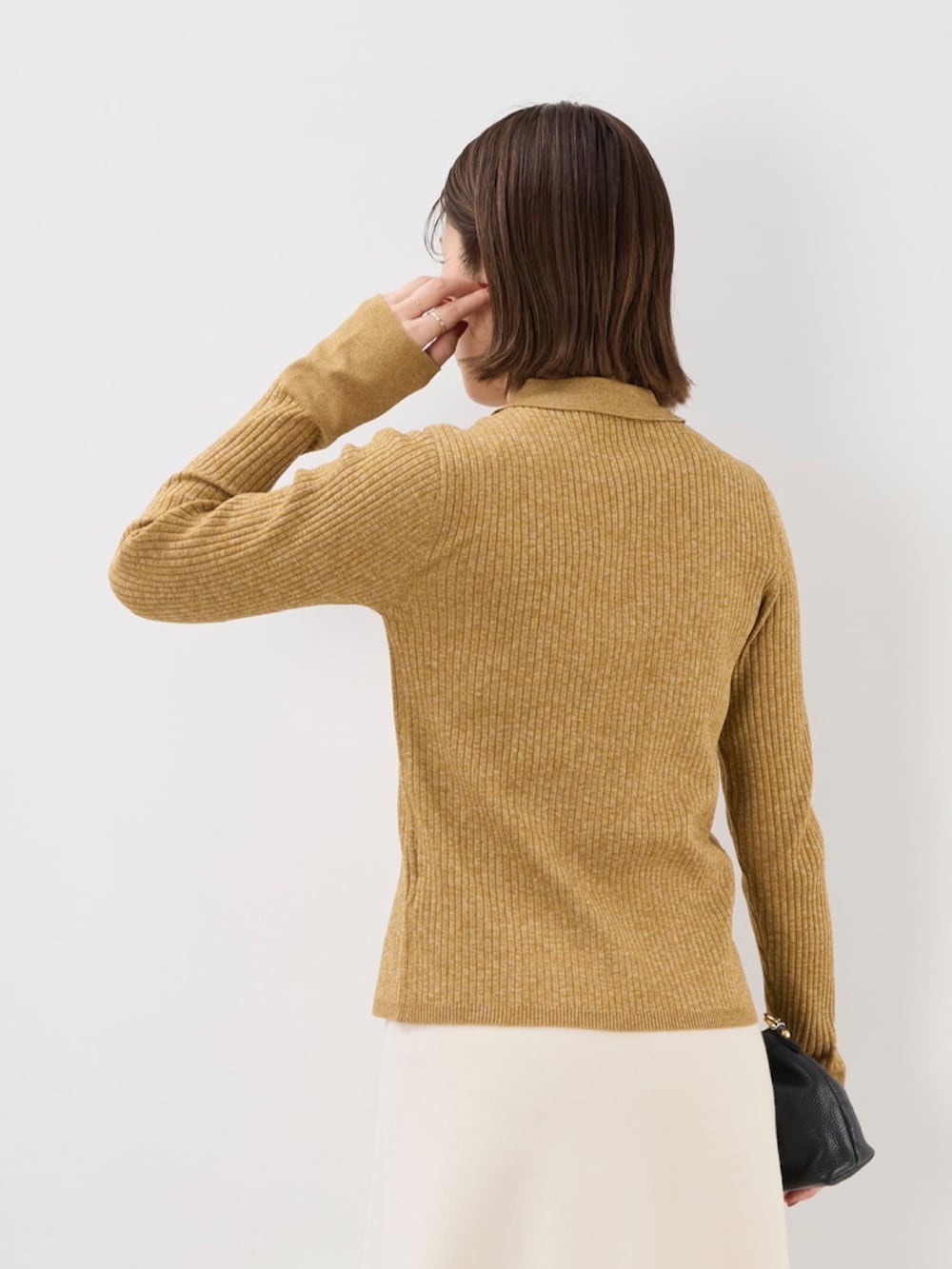 イエロー系のニット/セーター、ブラック系のショルダーバッグ、ホワイト系のスカートを着用したレディースの秋コーディネートの7枚目の写真