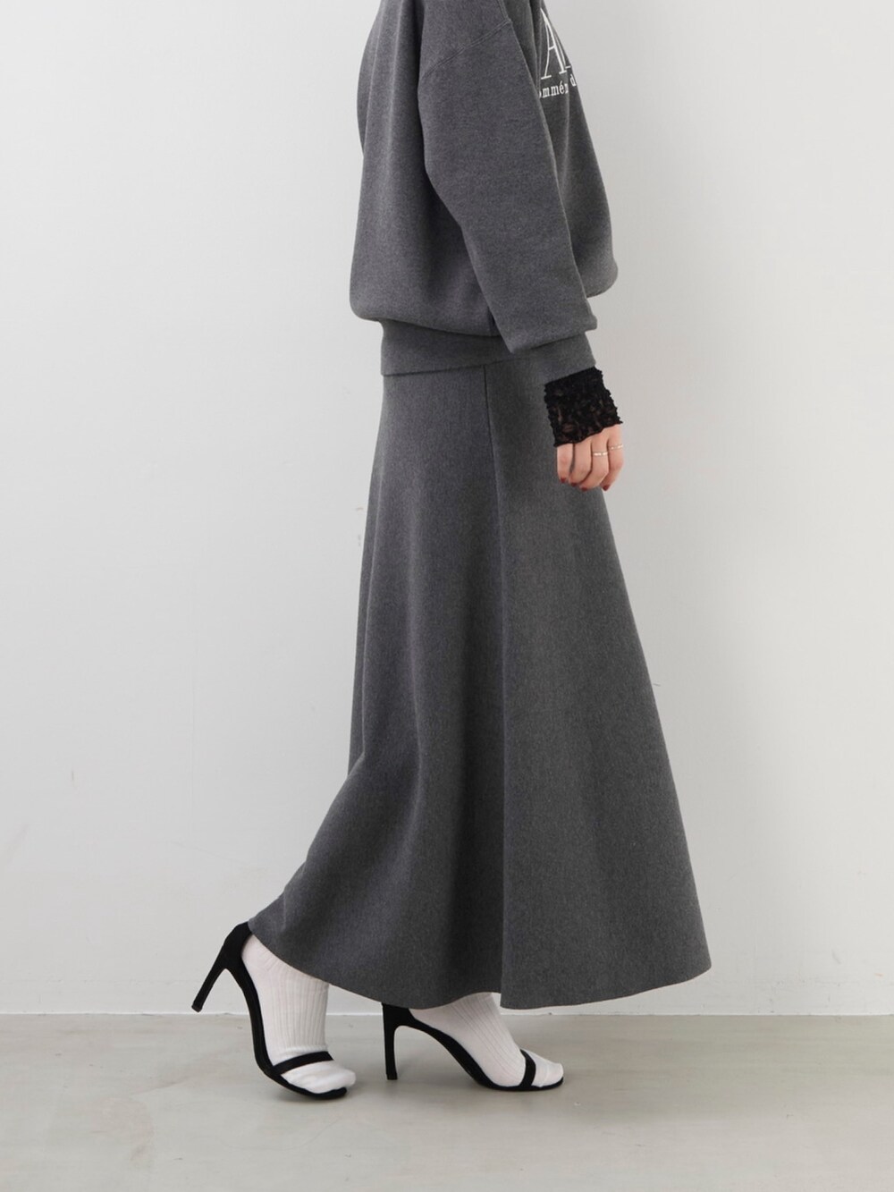 グレー系のニット/セーター、グレー系のスカート、ブラック系のTシャツ/カットソーを着用したレディースの秋コーディネートの5枚目の写真