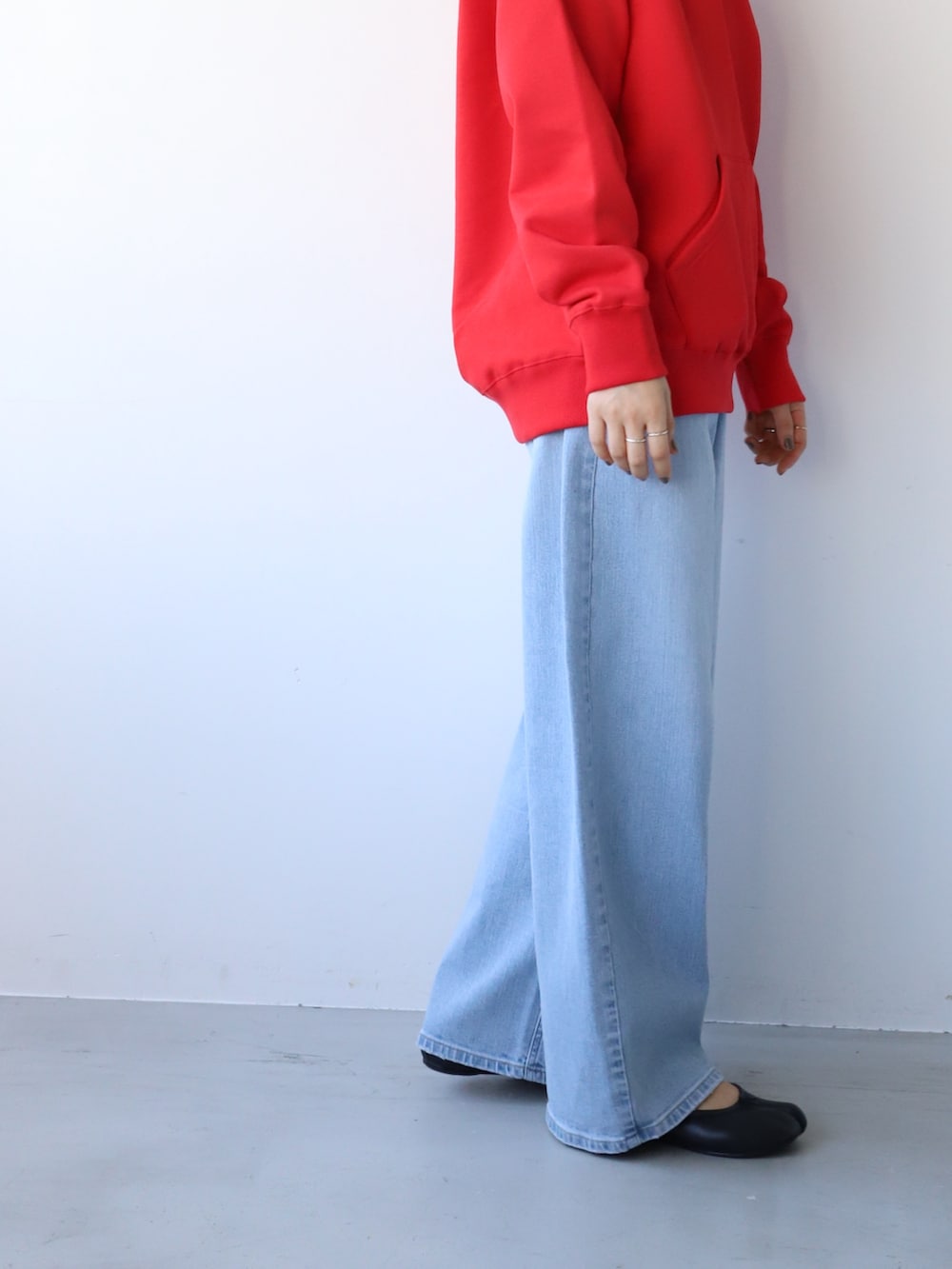 ブルー系のデニムパンツ、ブラック系のバレエシューズ、レッド系のパーカーを着用したレディースの秋コーディネートの3枚目の写真