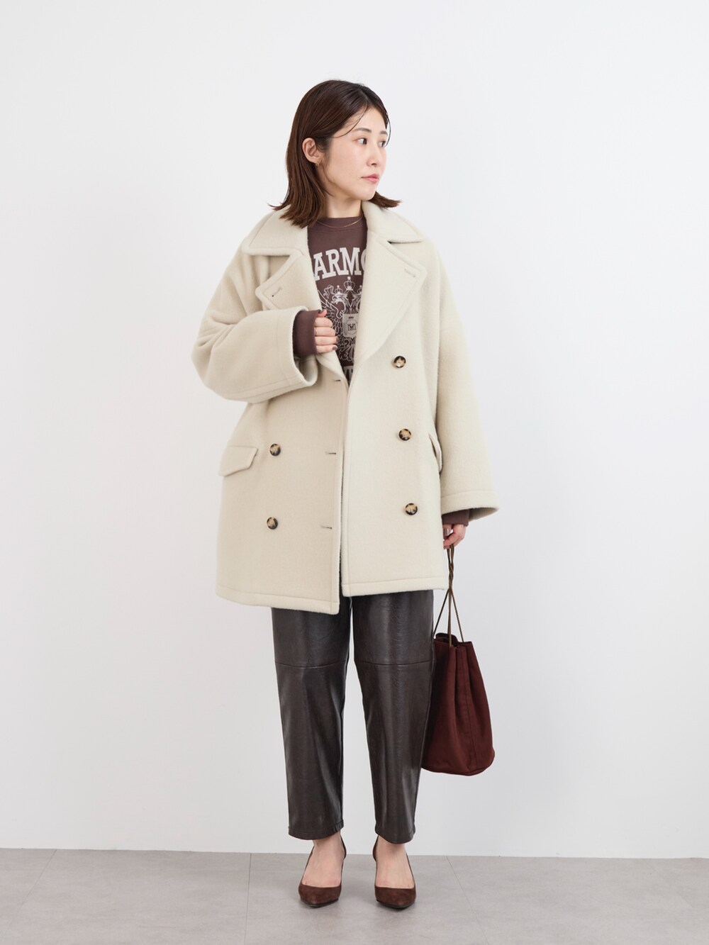 ブラウン系のスウェット、ホワイト系のTシャツ/カットソー、ベージュ系のピーコートを着用したレディースの冬コーディネートの2枚目の写真