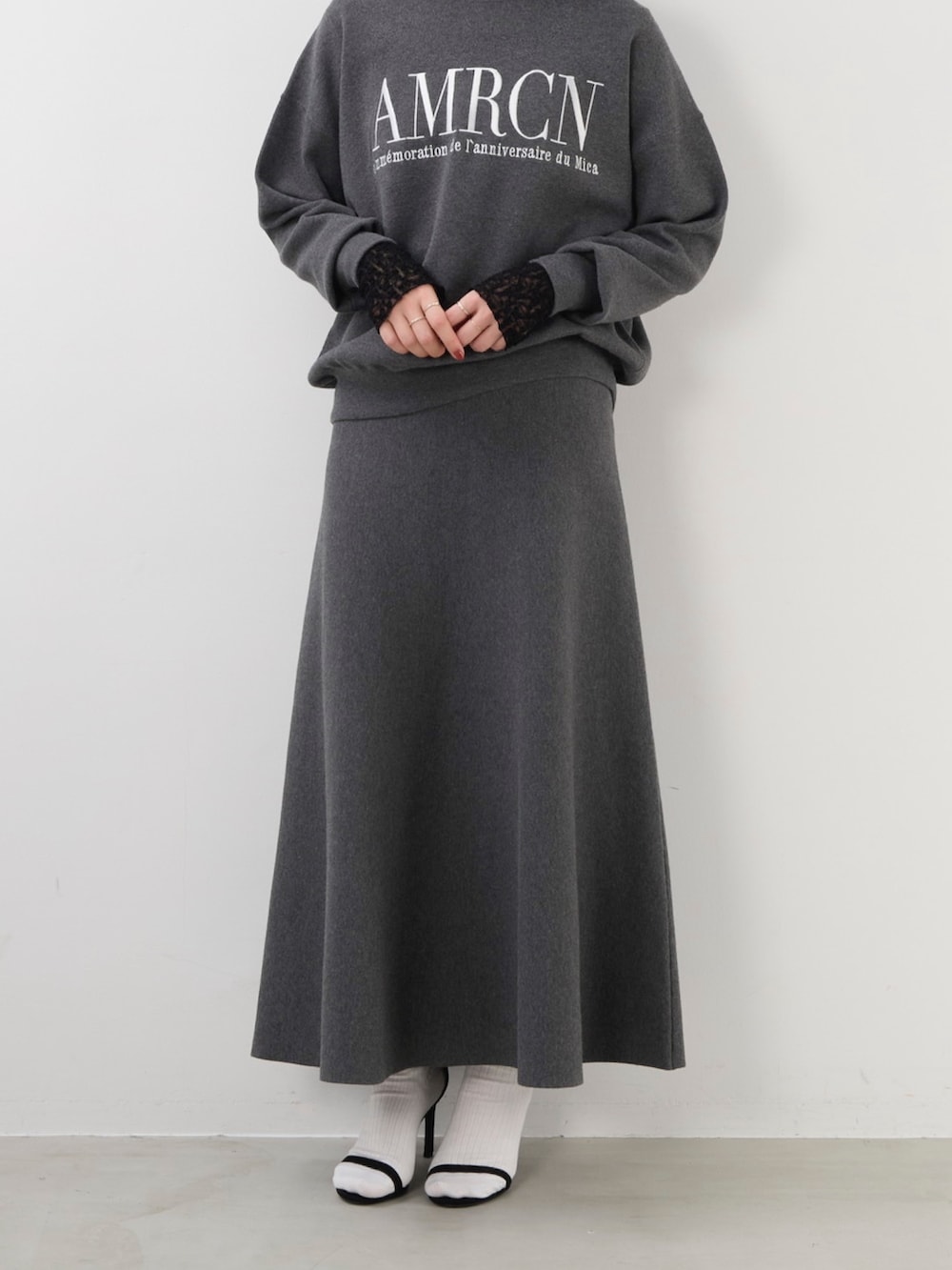 グレー系のニット/セーター、グレー系のスカート、ブラック系のTシャツ/カットソーを着用したレディースの秋コーディネートの3枚目の写真