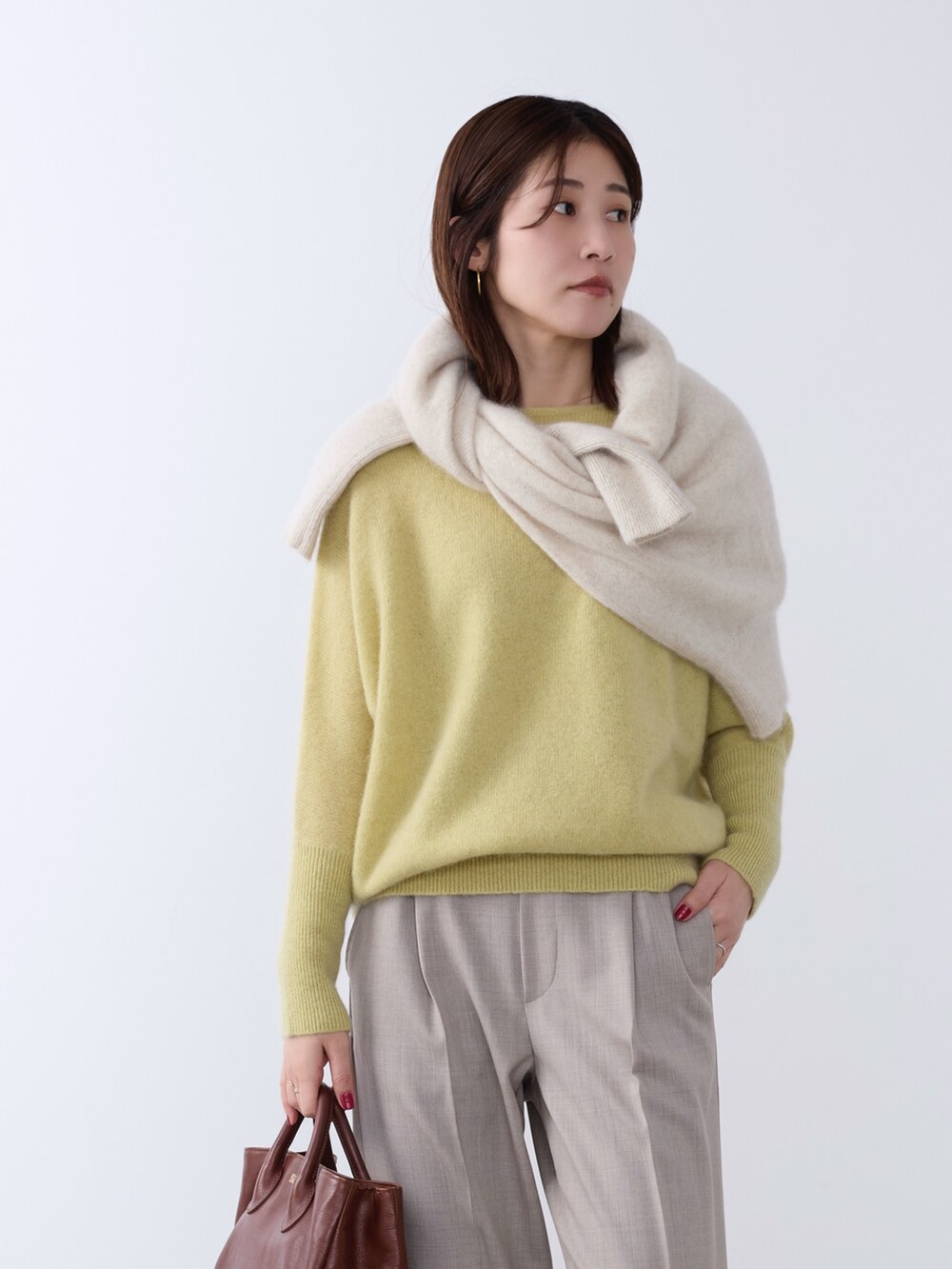 イエロー系のニット/セーター、ホワイト系のニット/セーター、ベージュ系のその他パンツを着用したレディースの冬コーディネートの3枚目の写真