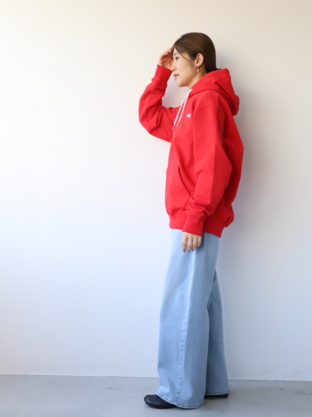 ブルー系のデニムパンツ、ブラック系のバレエシューズ、レッド系のパーカーを着用したレディースの秋コーディネートの2枚目の写真