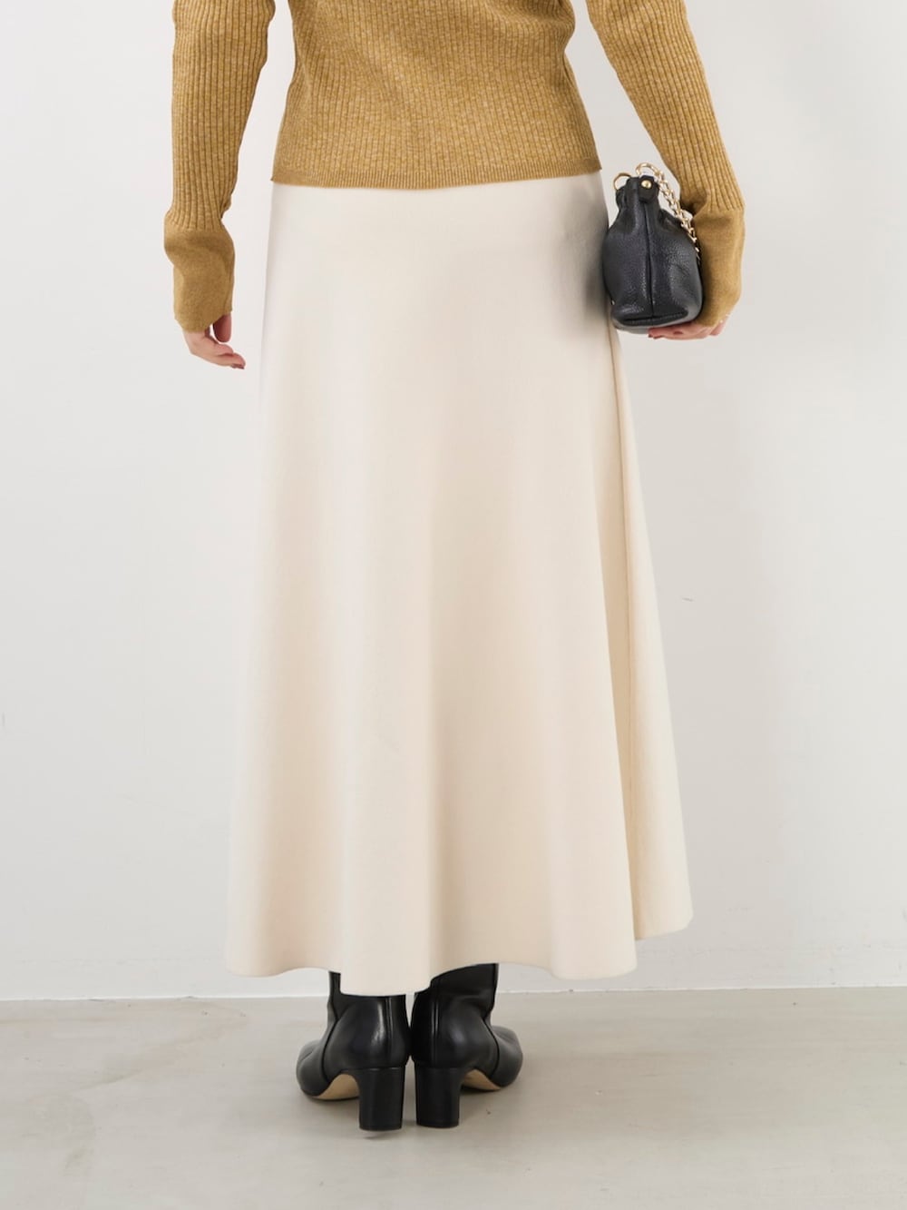 イエロー系のニット/セーター、ブラック系のショルダーバッグ、ホワイト系のスカートを着用したレディースの秋コーディネートの8枚目の写真